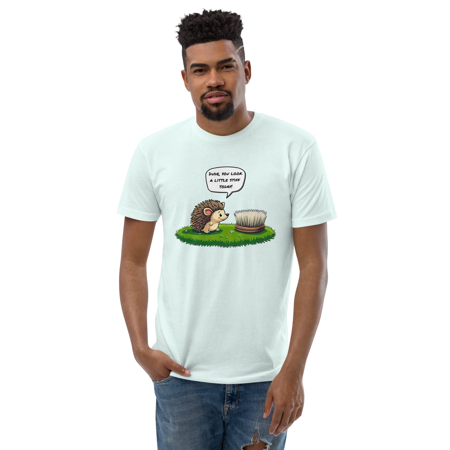 Product mockup. Man with short curly hair wearing a light blue t-shirt and jeans, shown from the front, printed with a cartoon hedgehog talking to a round brush and a humorous caption.