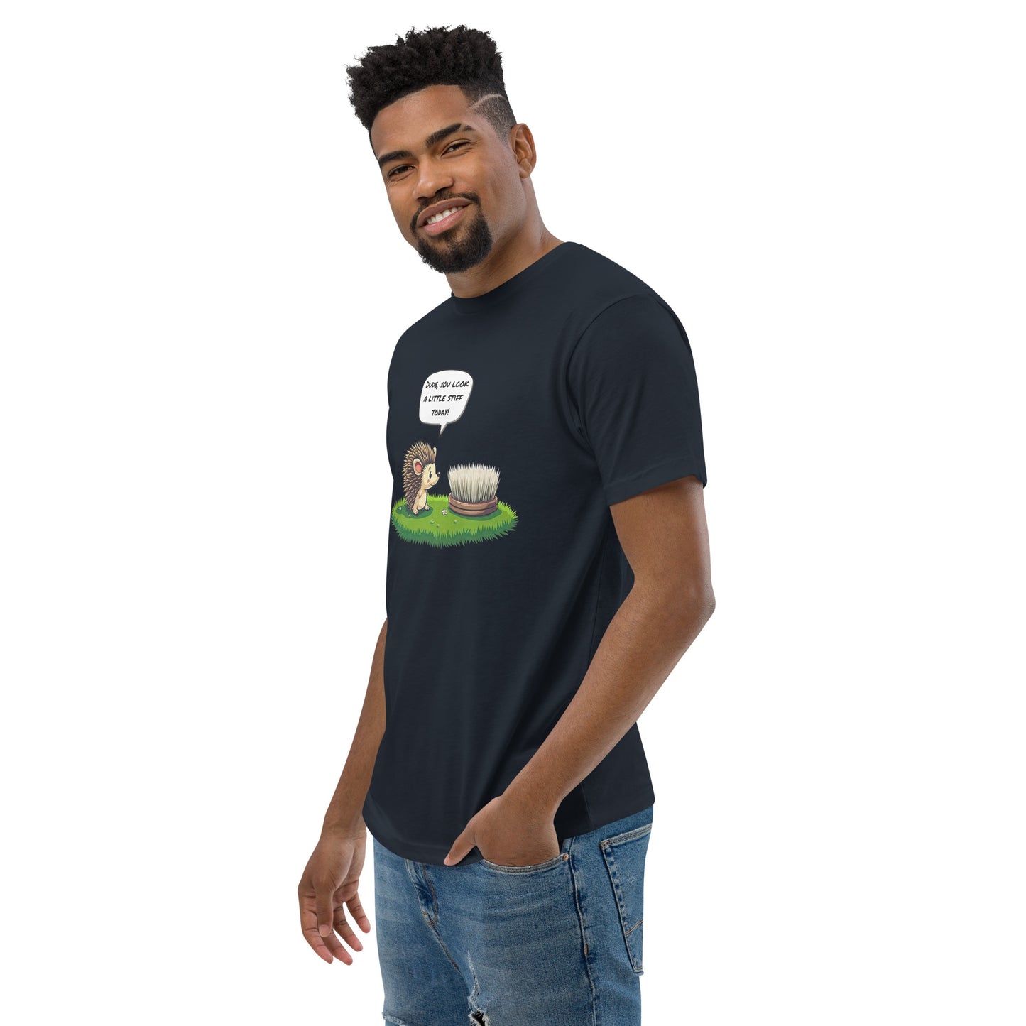 Product mockup. Man with short curly hair standing at an angle in a midnight navy t-shirt and jeans, featuring a cartoon hedgehog talking to a brush and a humorous caption.