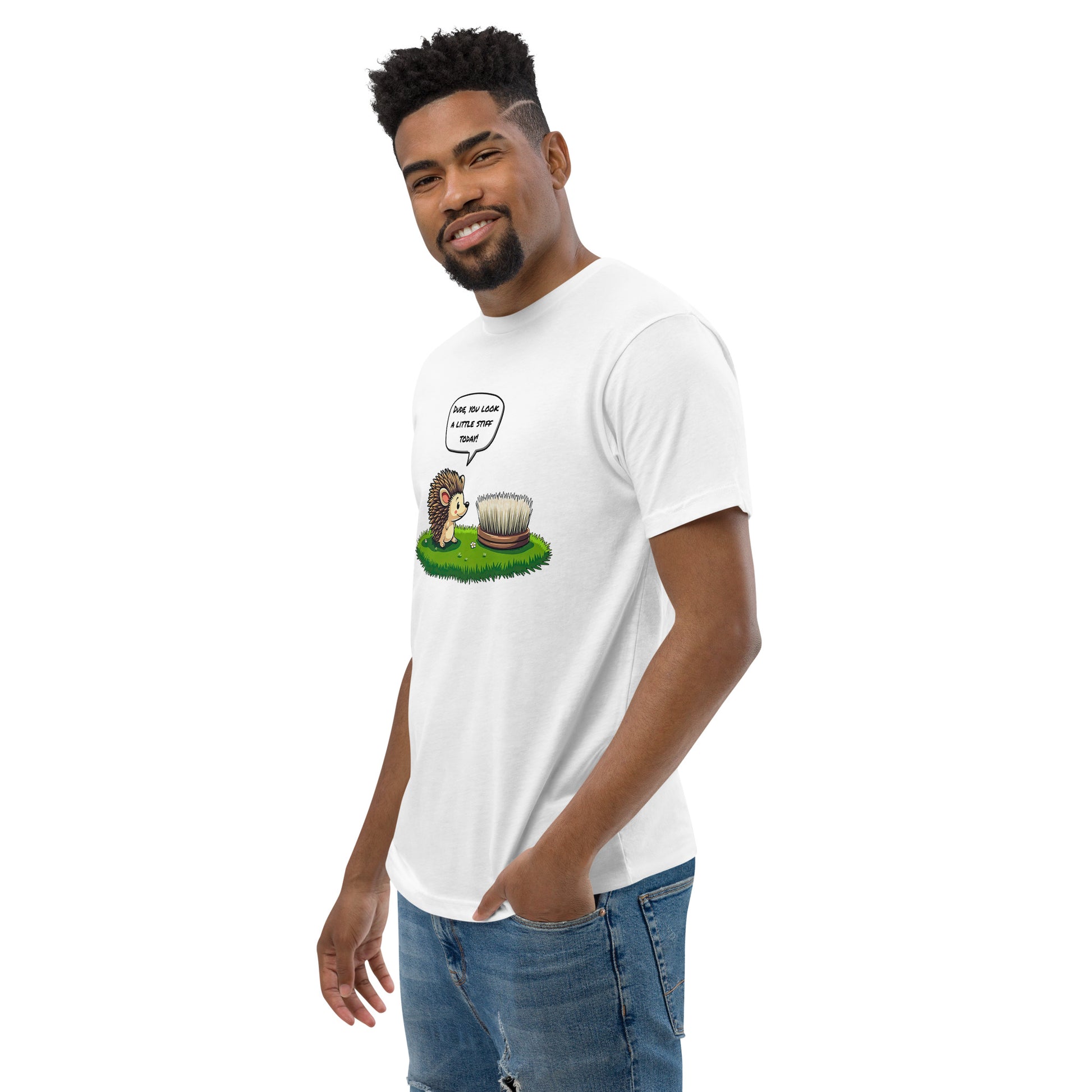 Product mockup. Man with short curly hair standing at an angle in a white t-shirt and jeans, featuring a cartoon hedgehog talking to a brush and a humorous caption.