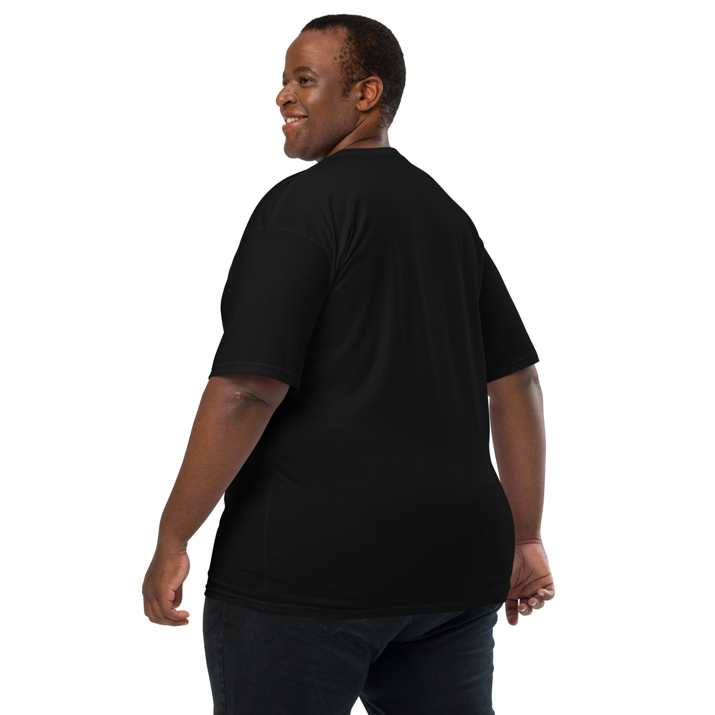 Product mockup. Man with short curly hair shown from behind, wearing a plain black heavyweight t-shirt and brick-colored pants, straight fit.