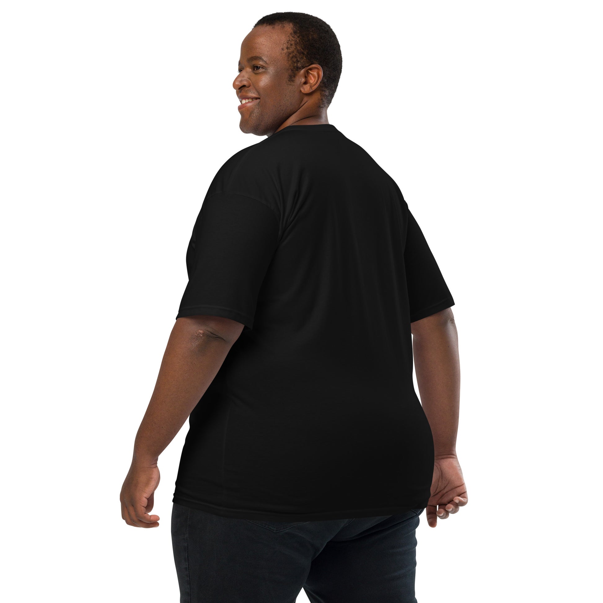 Product mockup. Man with short curly hair shown from behind, wearing a plain black heavyweight t-shirt and brick-colored pants, straight fit.