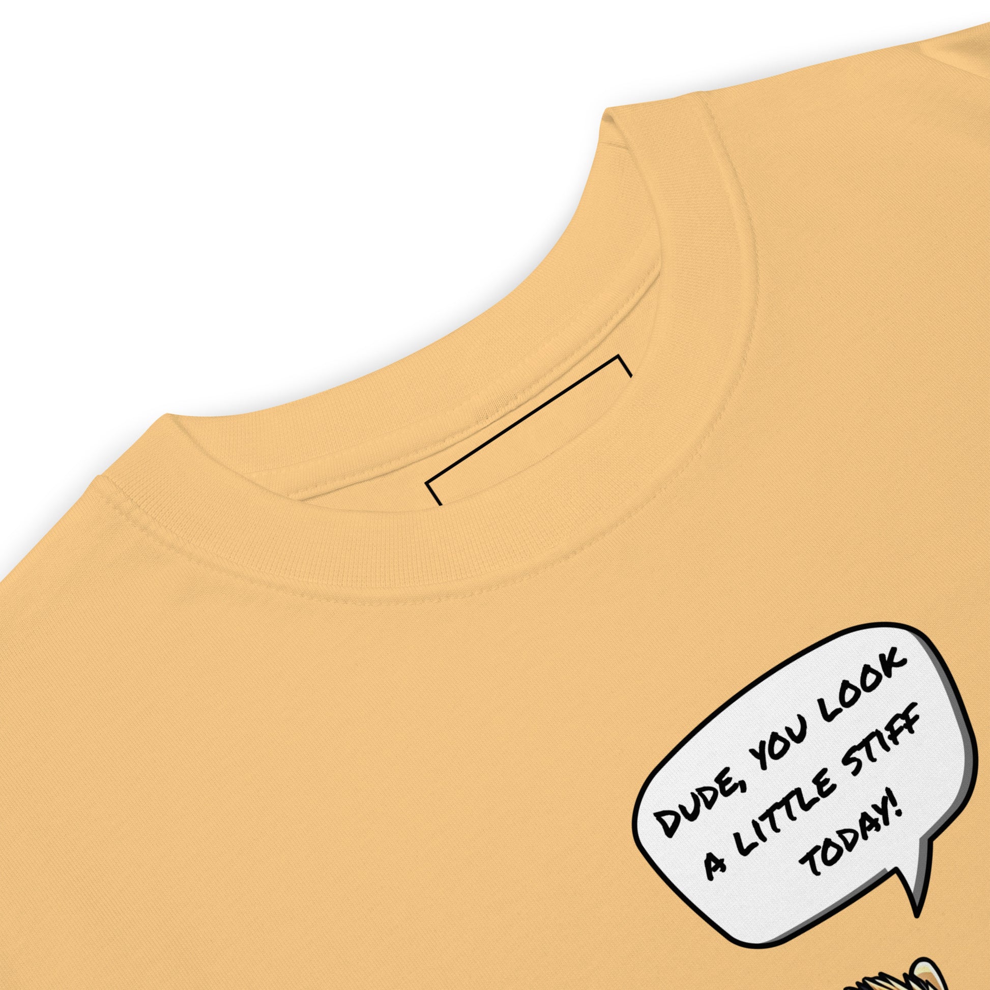 Close-up of the grabNade Men's Relaxed Heavyweight Tee in premium beige cotton, featuring a comic speech bubble: "DUDE, YOU LOOK A LITTLE STIFF TODAY!" Only the upper section with collar and part of the design is visible.