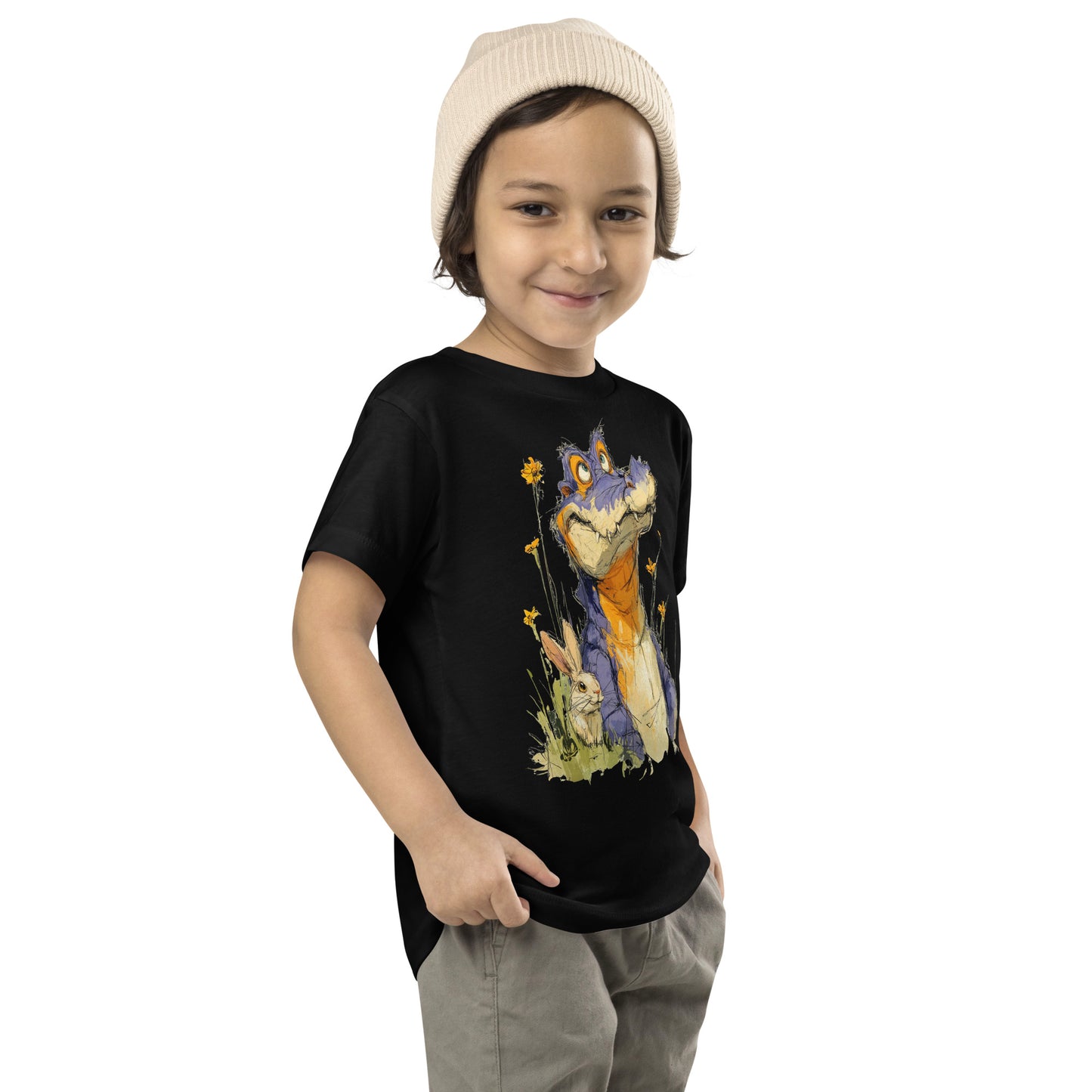Product mockup. A young child wearing a light beige knit beanie and a black t-shirt with a large, whimsical illustration of a friendly purple and orange cartoon dinosaur surrounded by yellow wildflowers, with a small rabbit nestled in the grass near its feet.