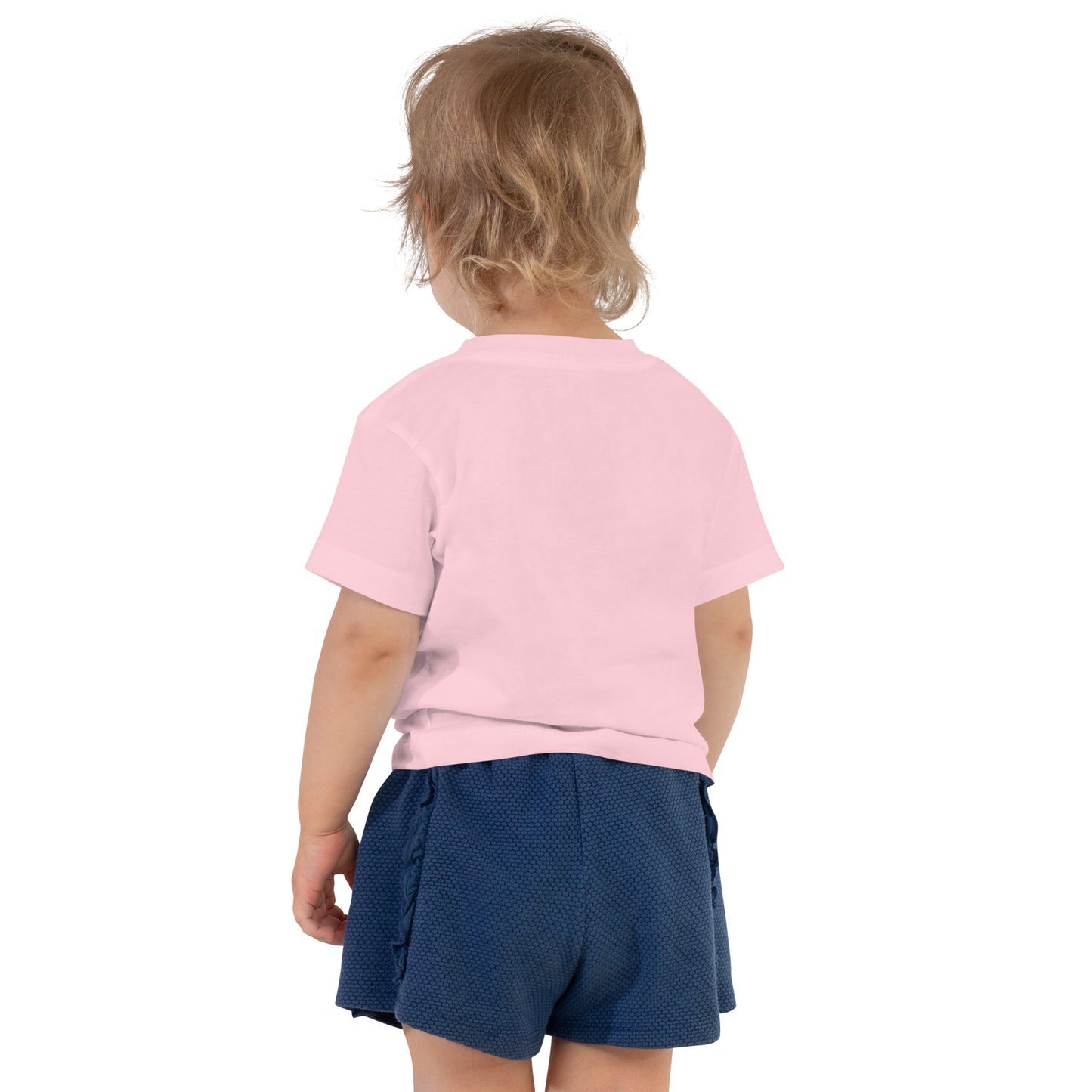 Product mockup. Toddler with light brown hair shown from behind, wearing a plain light pink t-shirt and blue shorts.