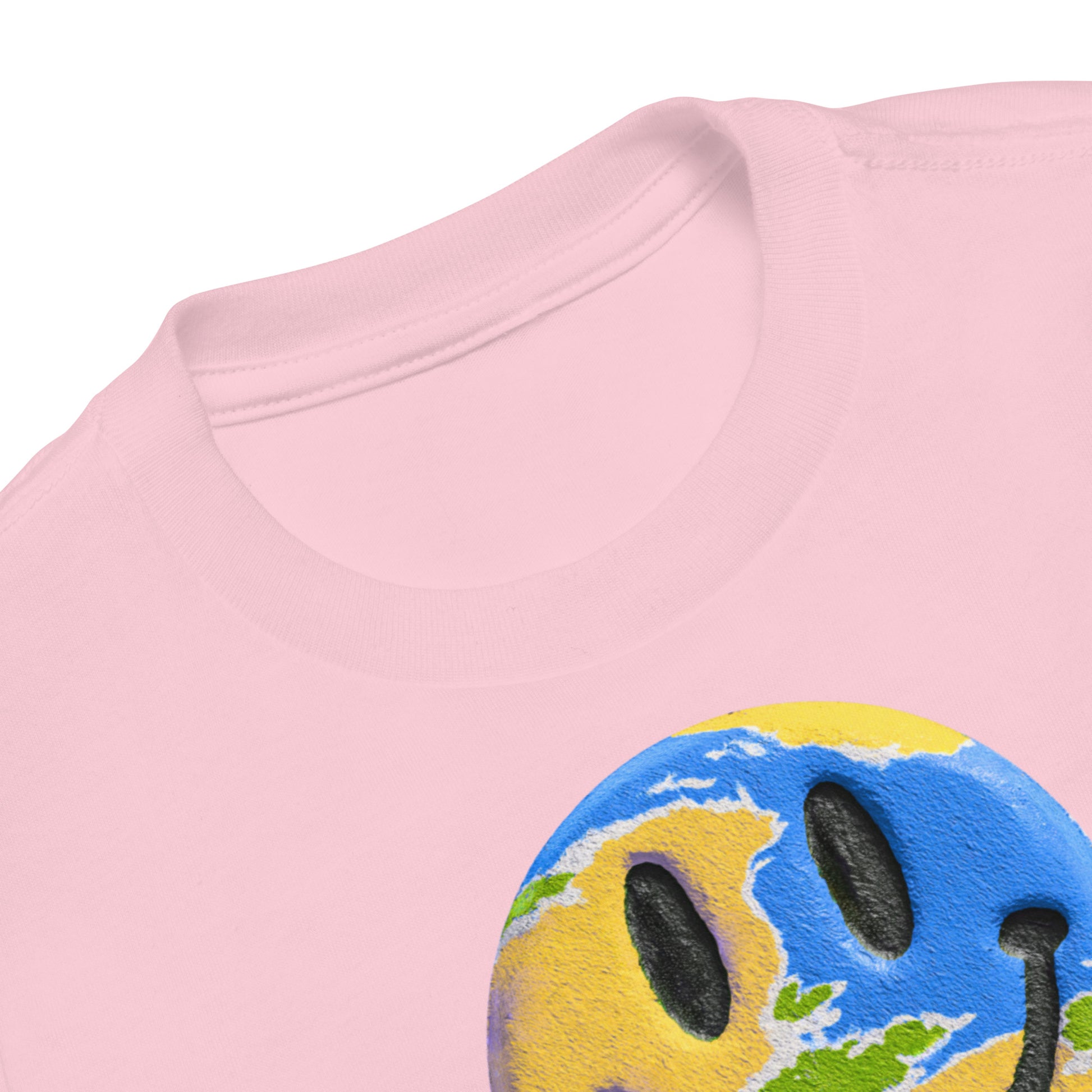 Product mockup. Close-up of a light pink t-shirt collar, showing a partial print of a blue and yellow smiley face with a world map design.