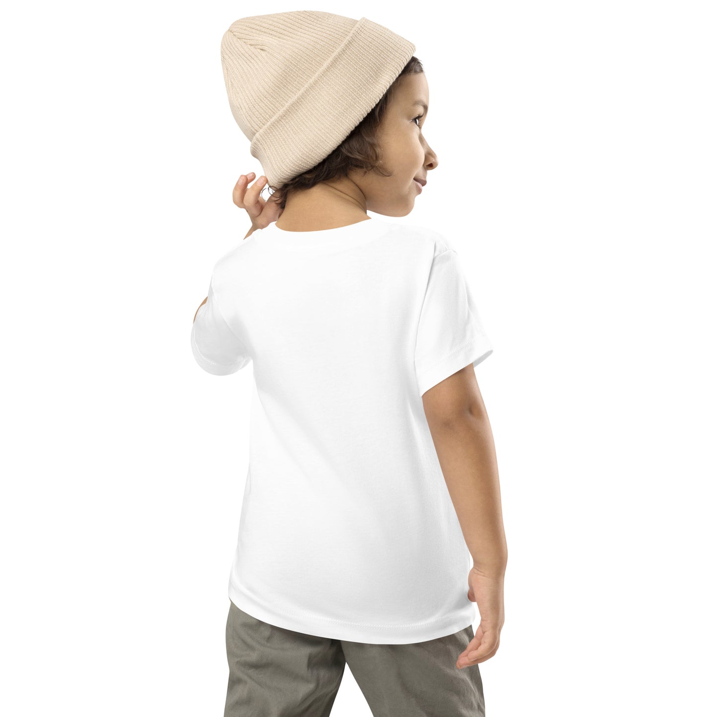 Product mockup. A young child shown from behind, wearing a light beige knit beanie, a plain white t-shirt with no visible graphics on the back, and light-colored pants. The child is looking over their shoulder with one arm slightly raised