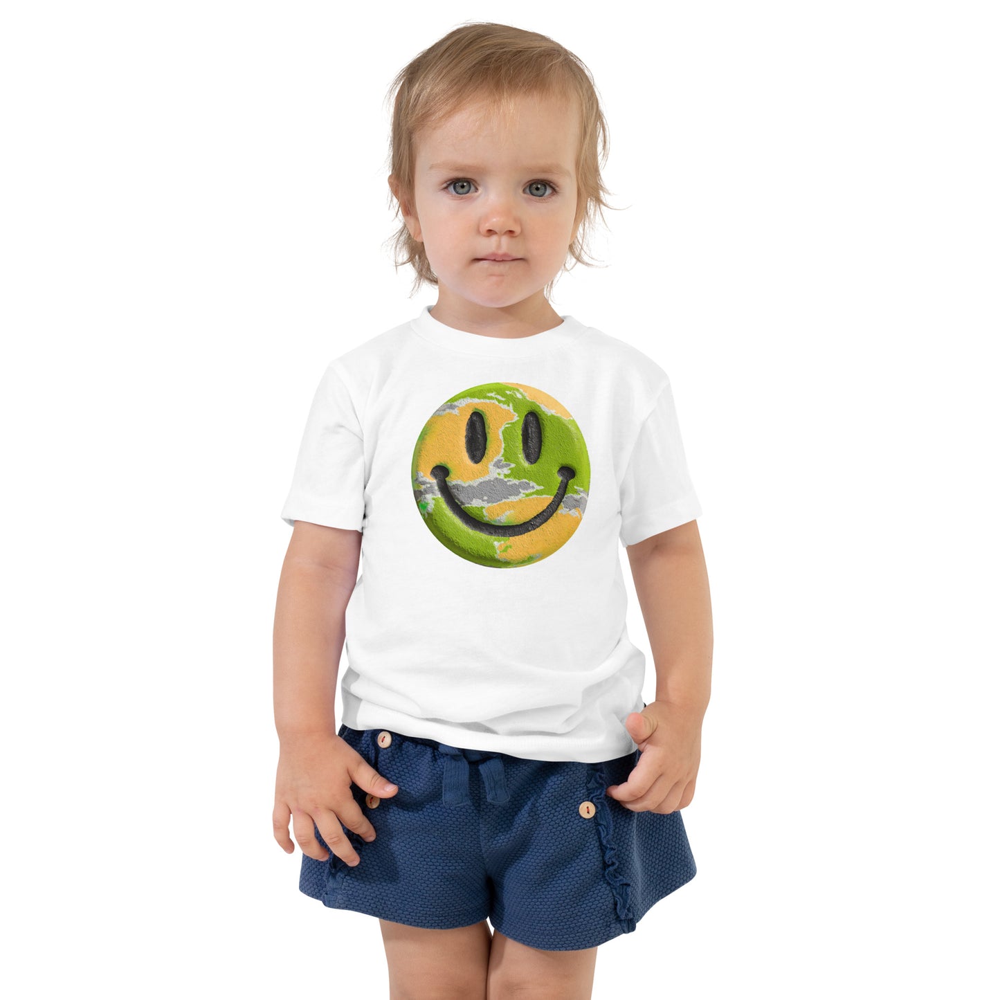 Product mockup. Toddler standing, wearing a white t-shirt with a large blue, yellow, and green smiley face icon, and blue jeans.