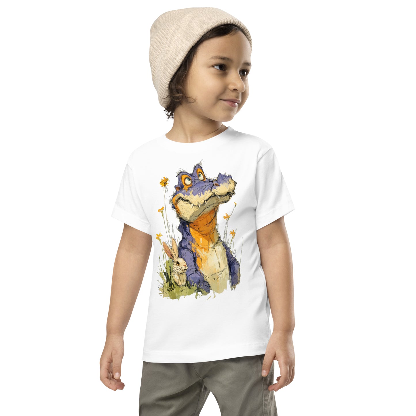 Product mockup. A young child wearing a light beige knit beanie and a white t-shirt with a large, whimsical illustration of a friendly purple and orange cartoon dinosaur surrounded by yellow wildflowers, with a small rabbit nestled in the grass near its feet.