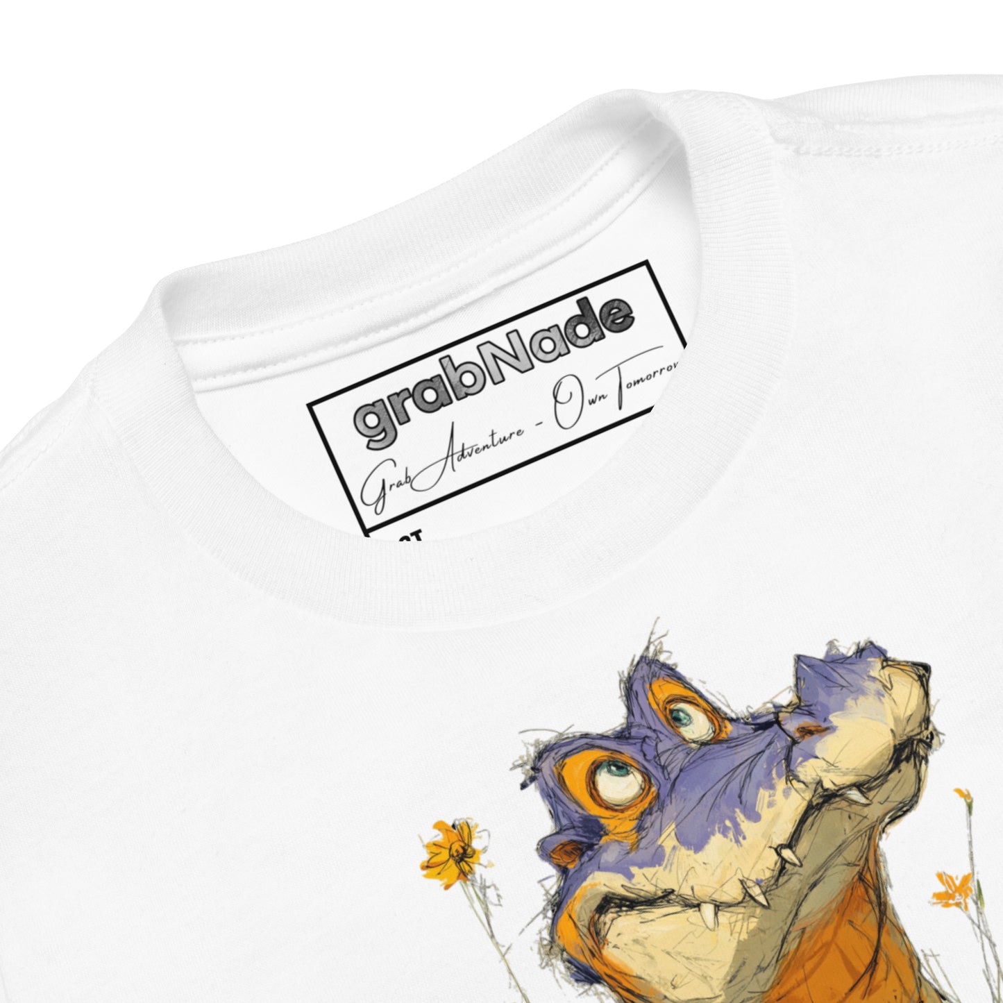 Product mockup. Close-up view of a white t-shirt collar showing the 'grabNade' brand label inside the neckline, with handwritten-style text beneath the brand name reading 'Grab Adventure - Own Tomorrow.' The shirt features part of a colorful cartoon illustration of a purple and orange dinosaur and yellow flowers visible below the collar.