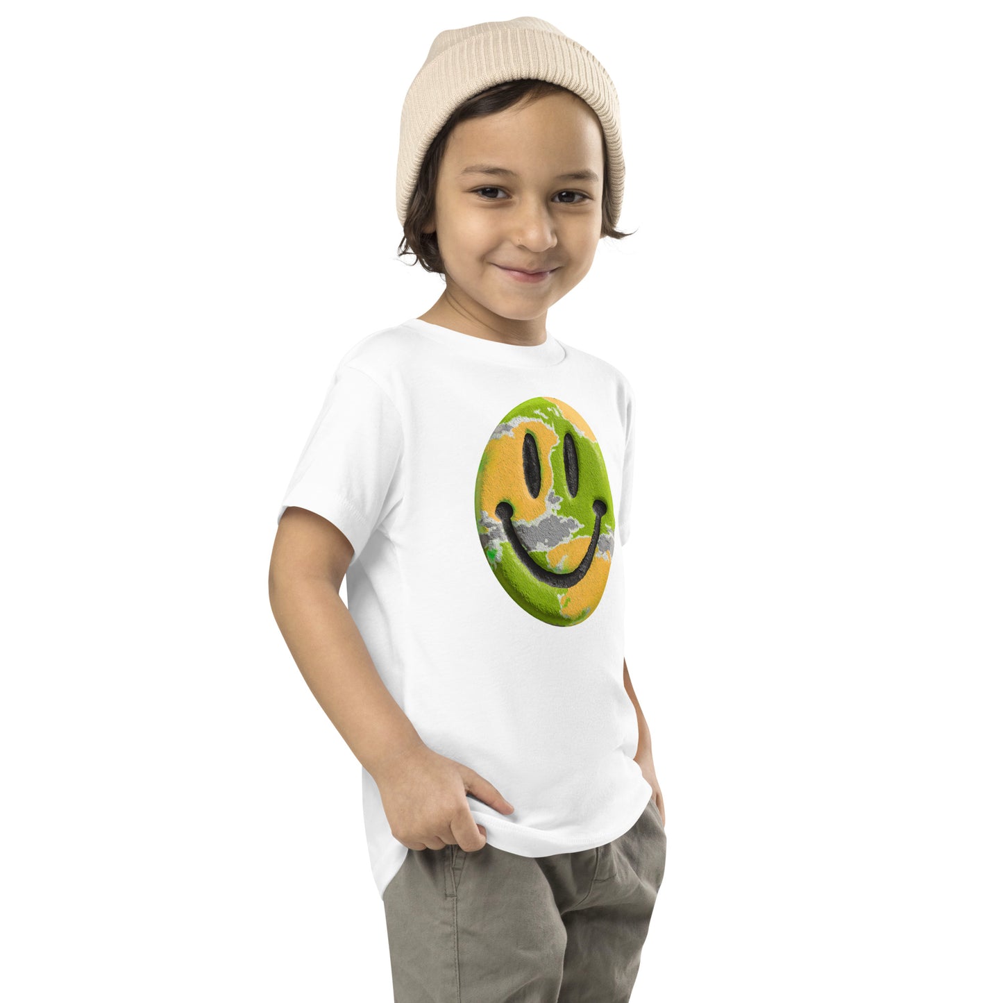 Product mockup. Child standing sideways, wearing a white t-shirt with a green and yellow smiley face icon, khaki pants, and beige hat.