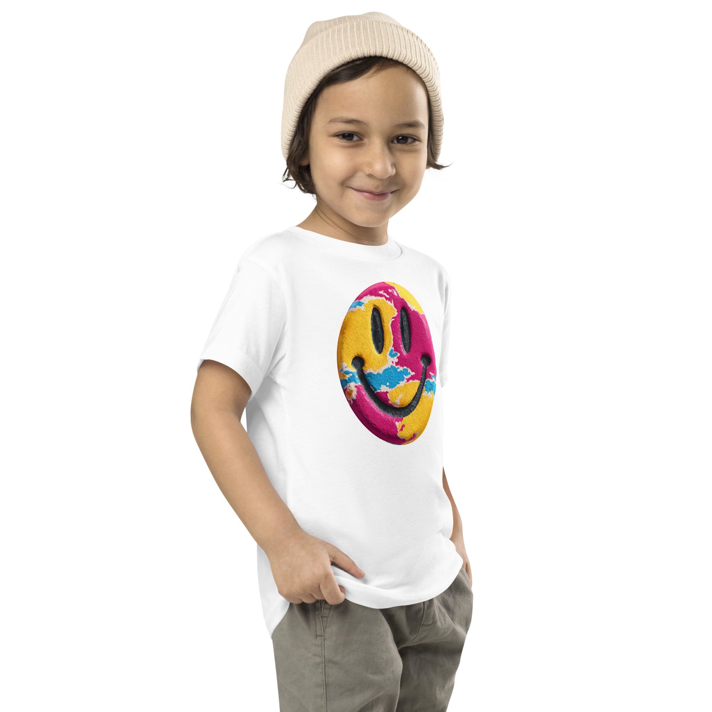 Product mockup. Child standing sideways, wearing a white t-shirt with a green and yellow smiley face icon, khaki pants, and beige hat.