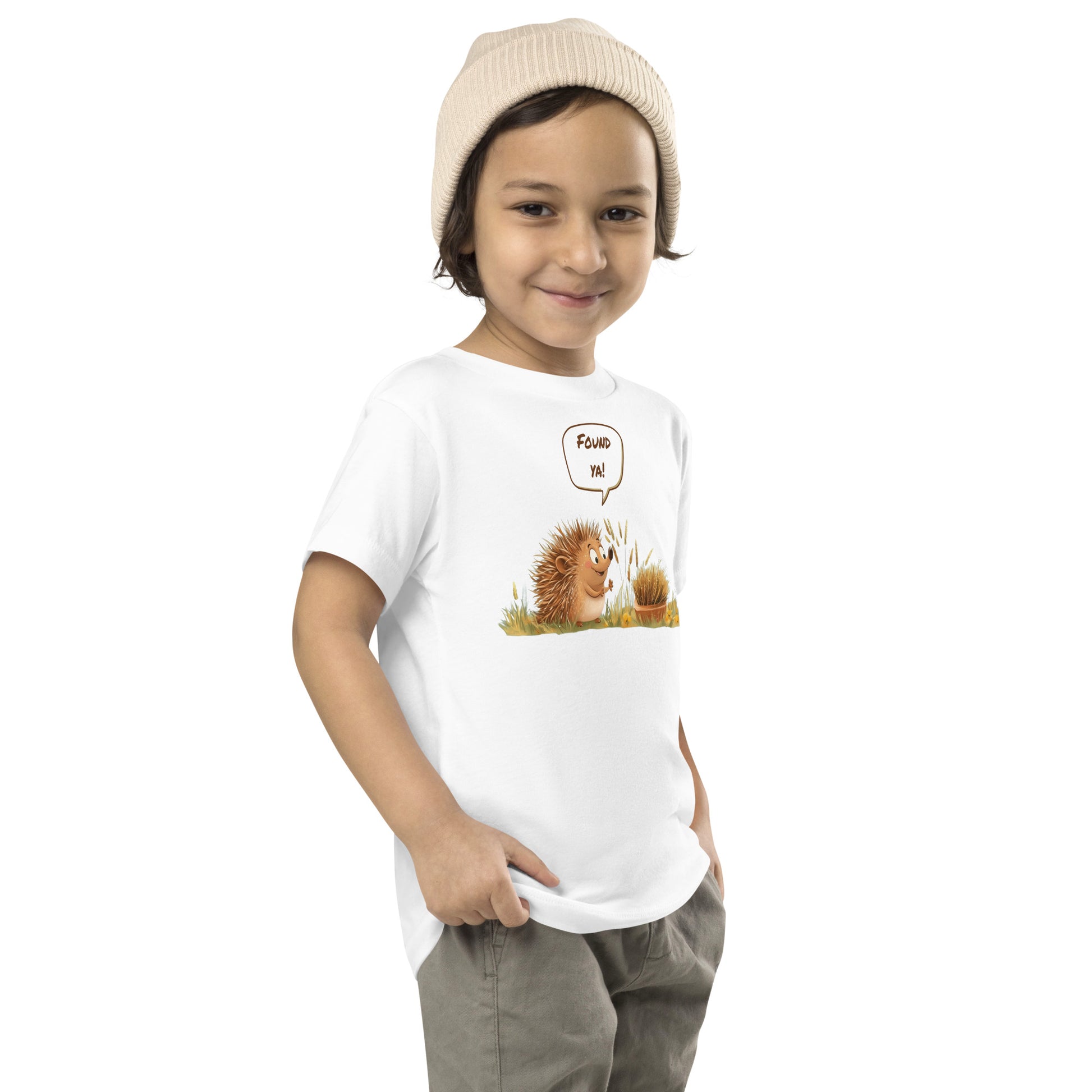 Product mockup. Child standing sideways, wearing a white t-shirt with a green and yellow smiley face icon, khaki pants, and beige hat.