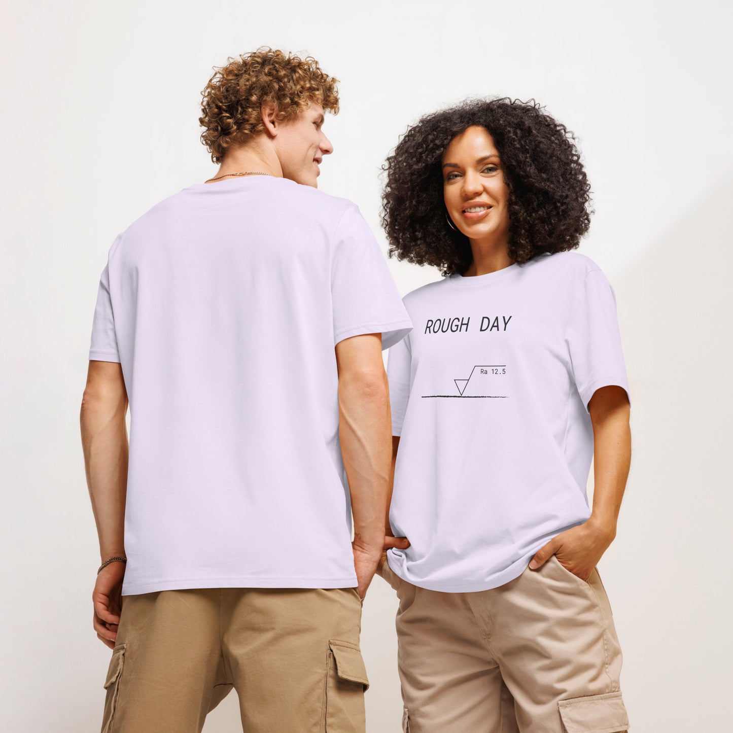 Man seen from behind and woman facing forward wearing lavender GOTS organic tee with roughness symbol and "ROUGH DAY (Ra 12.5)" text.