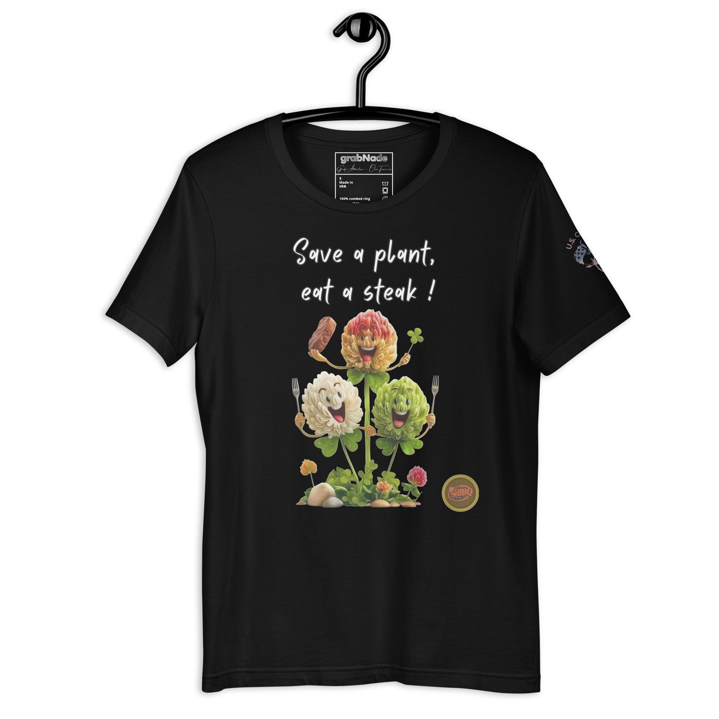 Product mockup. Black t-shirt on a hanger showing the design "Save a plant, eat a steak!" with playful cartoon clovers and utensils on the front.