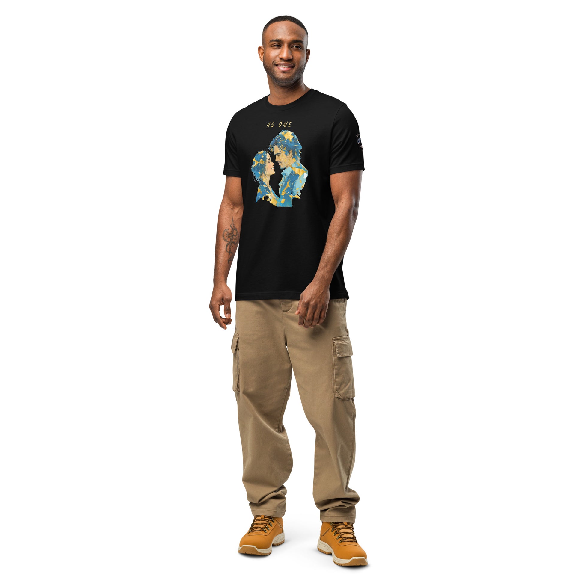 Product mockup. A man stands wearing a black t-shirt with an abstract blue and yellow silhouette graphic of two faces and the text "AS ONE" above.