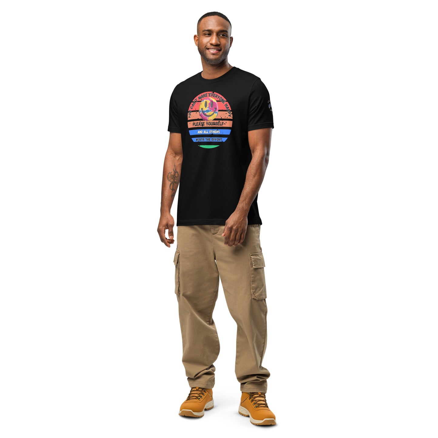 Product mockup. A man stands wearing a black t-shirt featuring a circular rainbow-striped graphic with a smiley face and layered positive messages.
