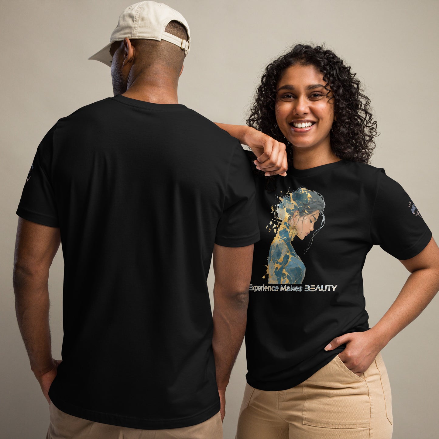 Product mockup. A man and woman stand together; the woman wears a black t-shirt with an abstract blue and yellow illustration and the phrase "Experience Makes BEAUTY" on the front, while the man shows the back of his plain black t-shirt.