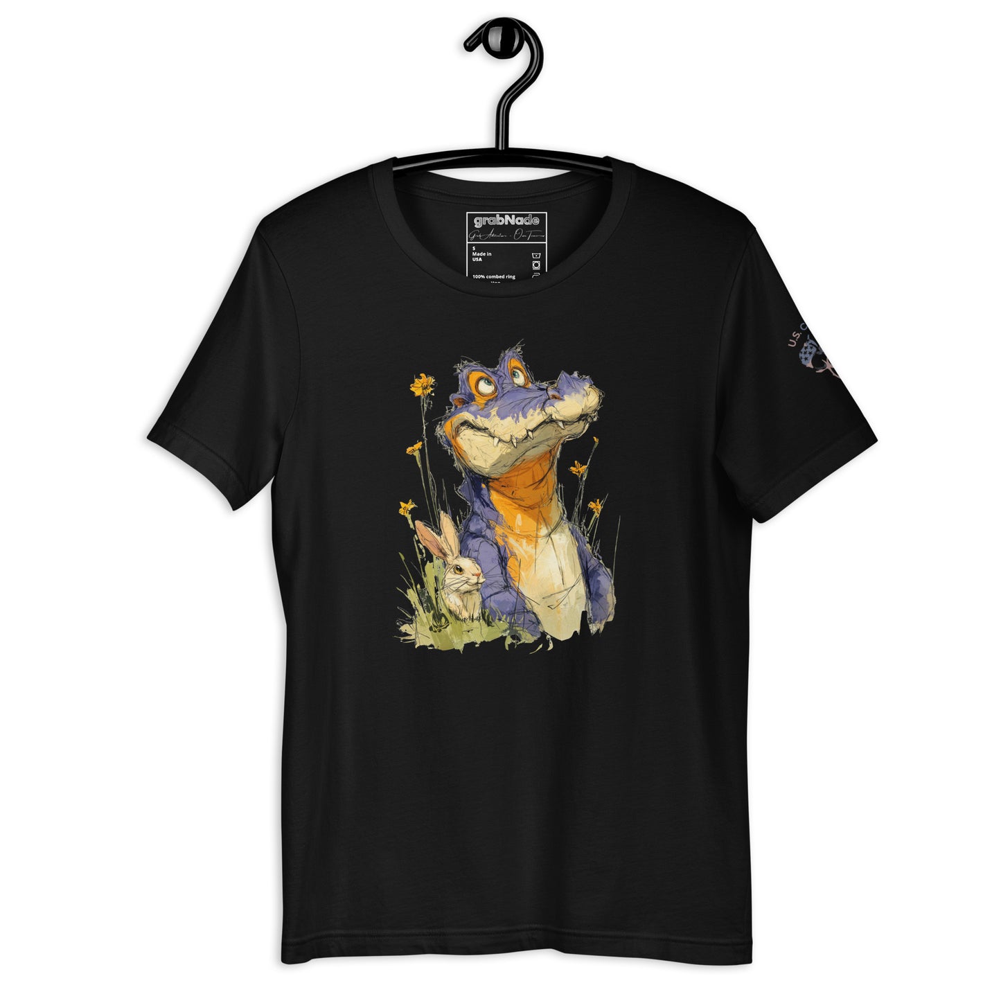Product mockup. Black t-shirt on a hanger featuring a playful cartoon alligator with orange and blue colors, sitting in grass among flowers and a rabbit.