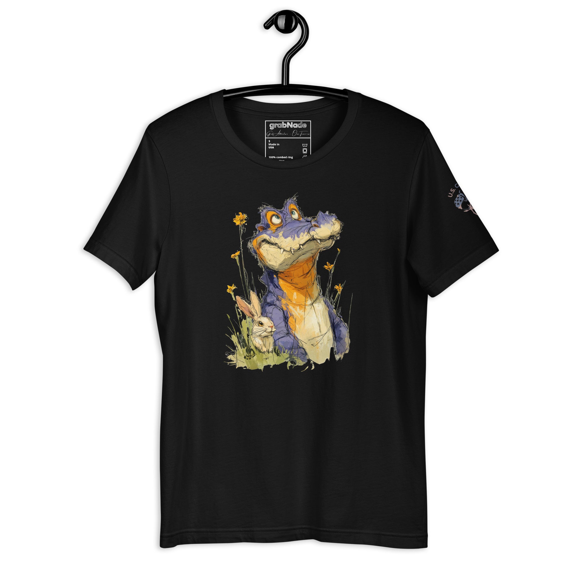 Product mockup. Black t-shirt on a hanger featuring a playful cartoon alligator with orange and blue colors, sitting in grass among flowers and a rabbit.