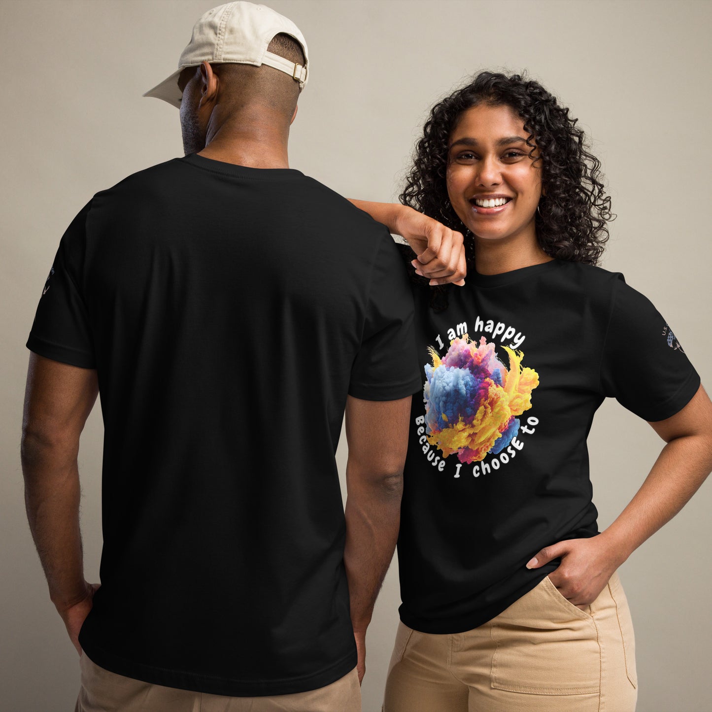 Product mockup. A man and woman stand together; the woman wears a black t-shirt with colorful text "I am happy because I choose to" around a bright swirling abstract cloud, while the man shows the back of a plain black t-shirt.