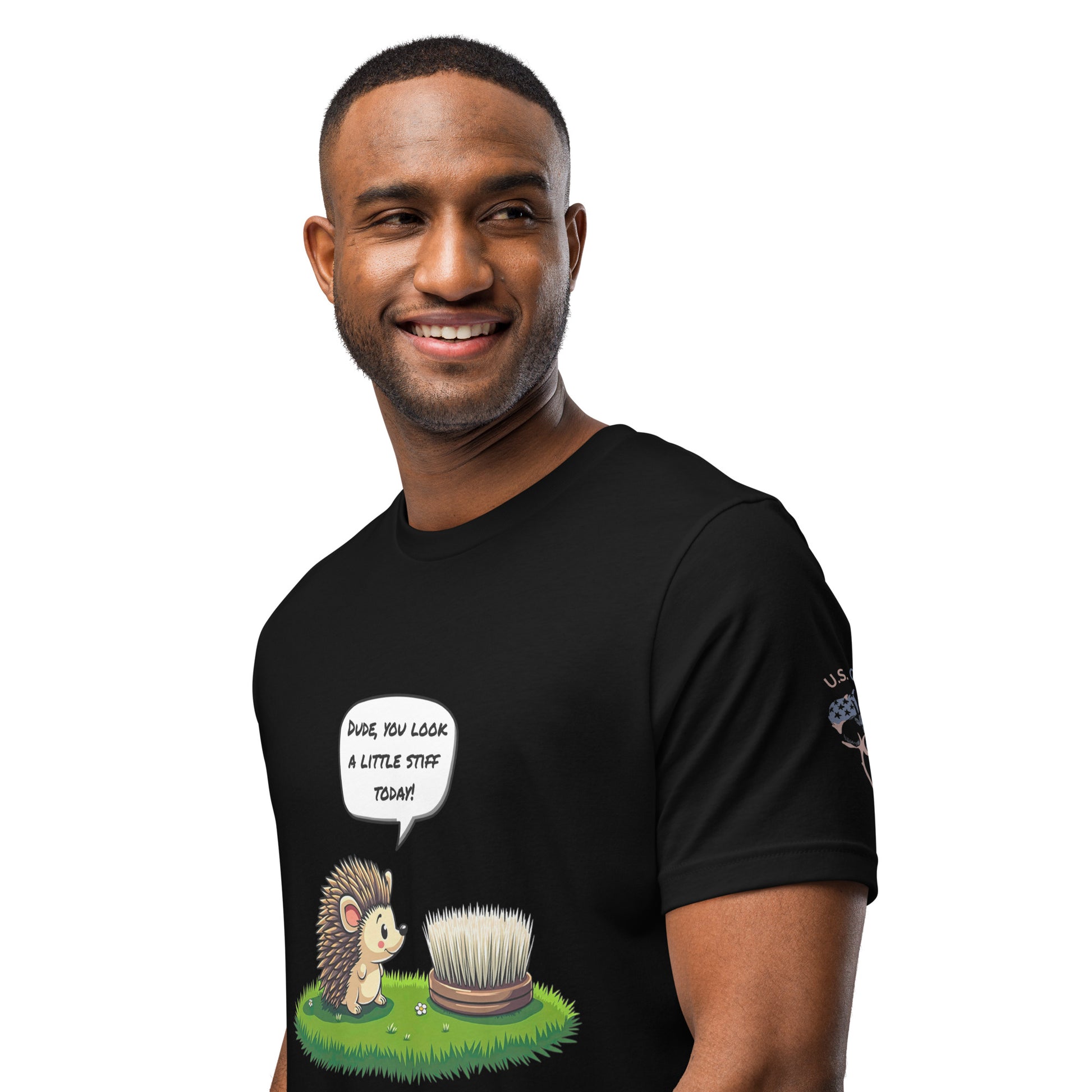 Product mockup. A man wears a black t-shirt illustrated with a cartoon hedgehog talking to a scrubbing brush, saying "Dude, you look a little stiff today!"