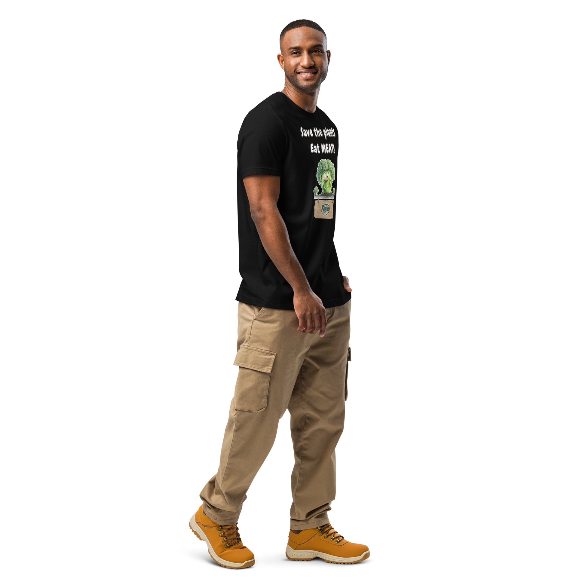 Product mockup. A man models a black t-shirt with "Save the plants Eat MEAT!" above a cartoon broccoli, khaki pants, and tan boots.