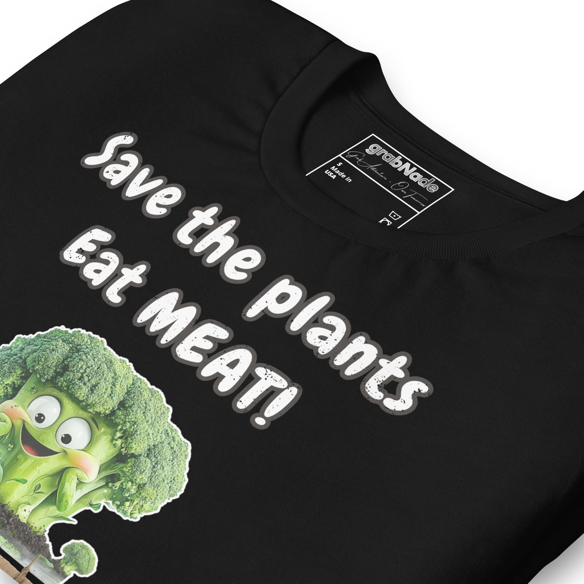 Product mockup. Close-up of a black t-shirt with "Save the plants Eat MEAT!" and a smiling cartoon broccoli illustration.