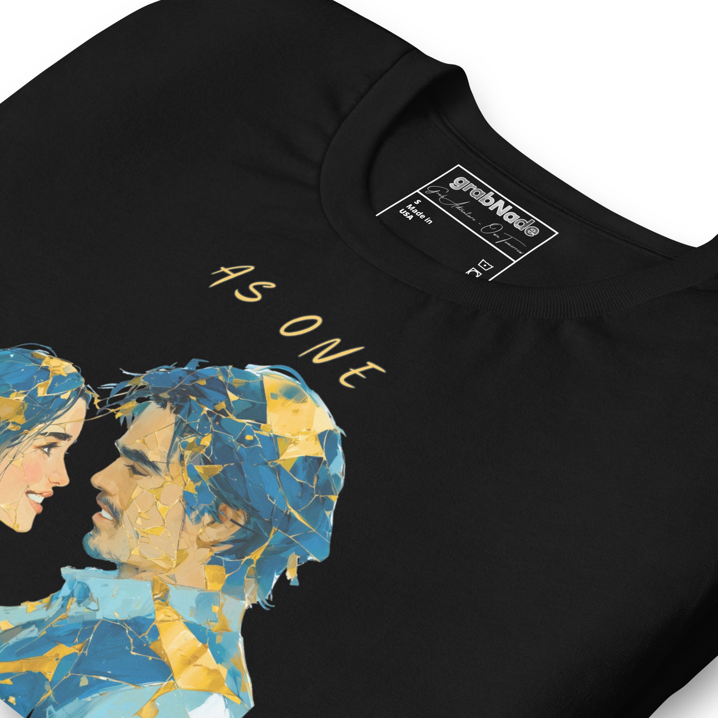 Product mockup. Close-up of a black t-shirt with two figures facing each other, their faces fragmented in blue and gold, and the phrase "AS ONE" above.
