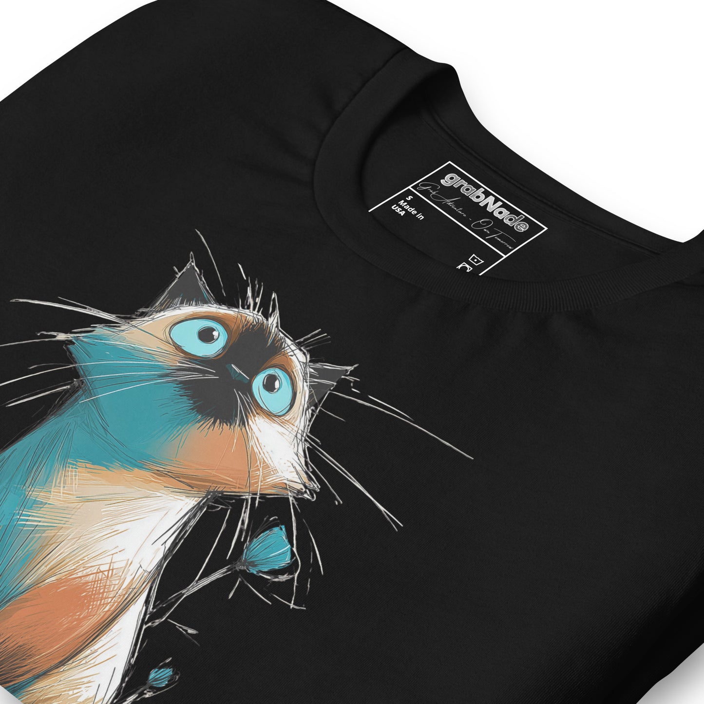 Product mockup. Close-up of a black t-shirt showing a stylized cartoon cat with blue eyes and fur in blue, orange, and white.