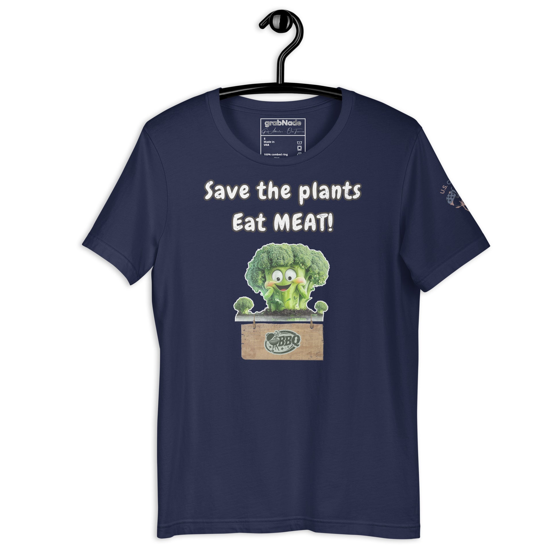 Product mockup. Navy blue t-shirt on a hanger, printed with a smiling green broccoli above a crate and the phrase “Save the plants Eat MEAT!”.