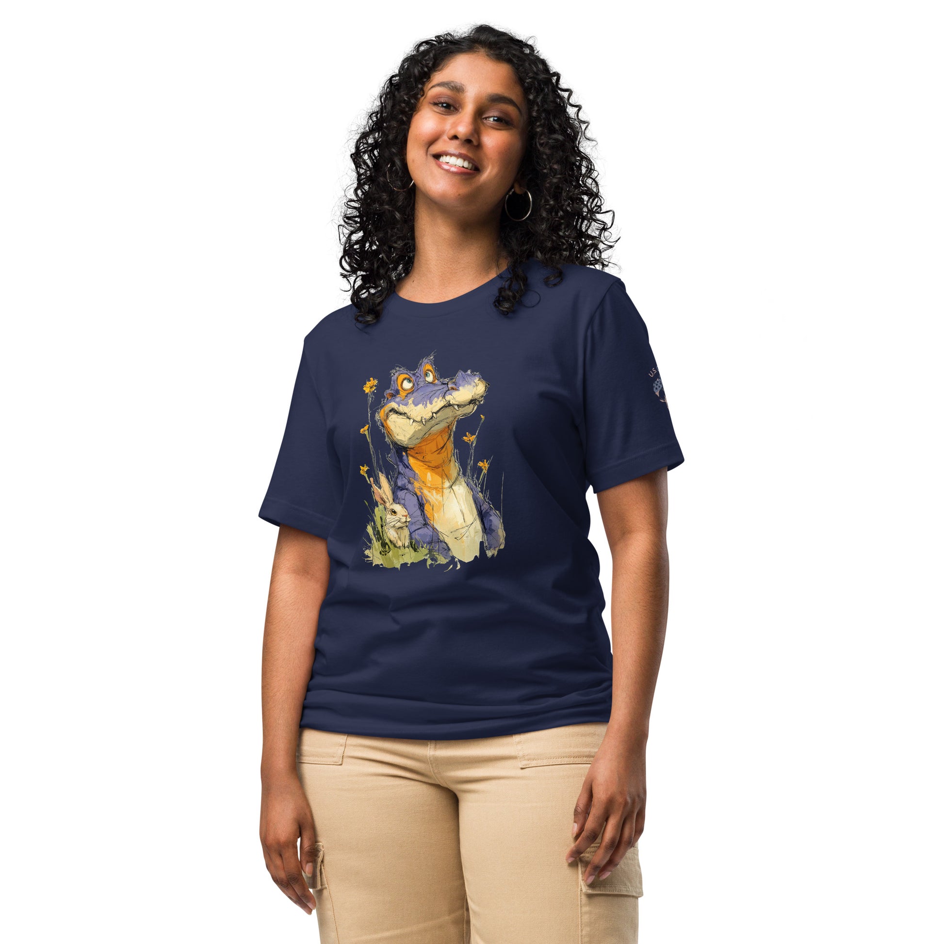 Product mockup. Smiling woman in beige pants wearing a navy t-shirt with an illustrated purple cartoon alligator in yellow flowers and grass, a bunny sitting nearby.