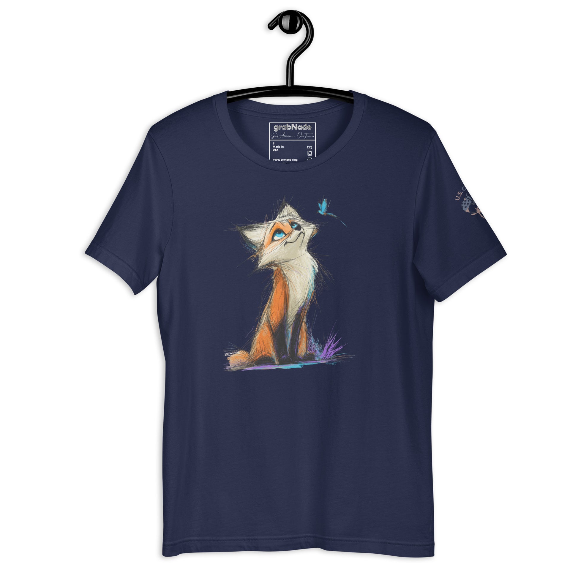 Product mockup. Navy blue t-shirt on a hanger, decorated with a colorful sketch-style fox sitting on grass, looking up at a small blue bird.