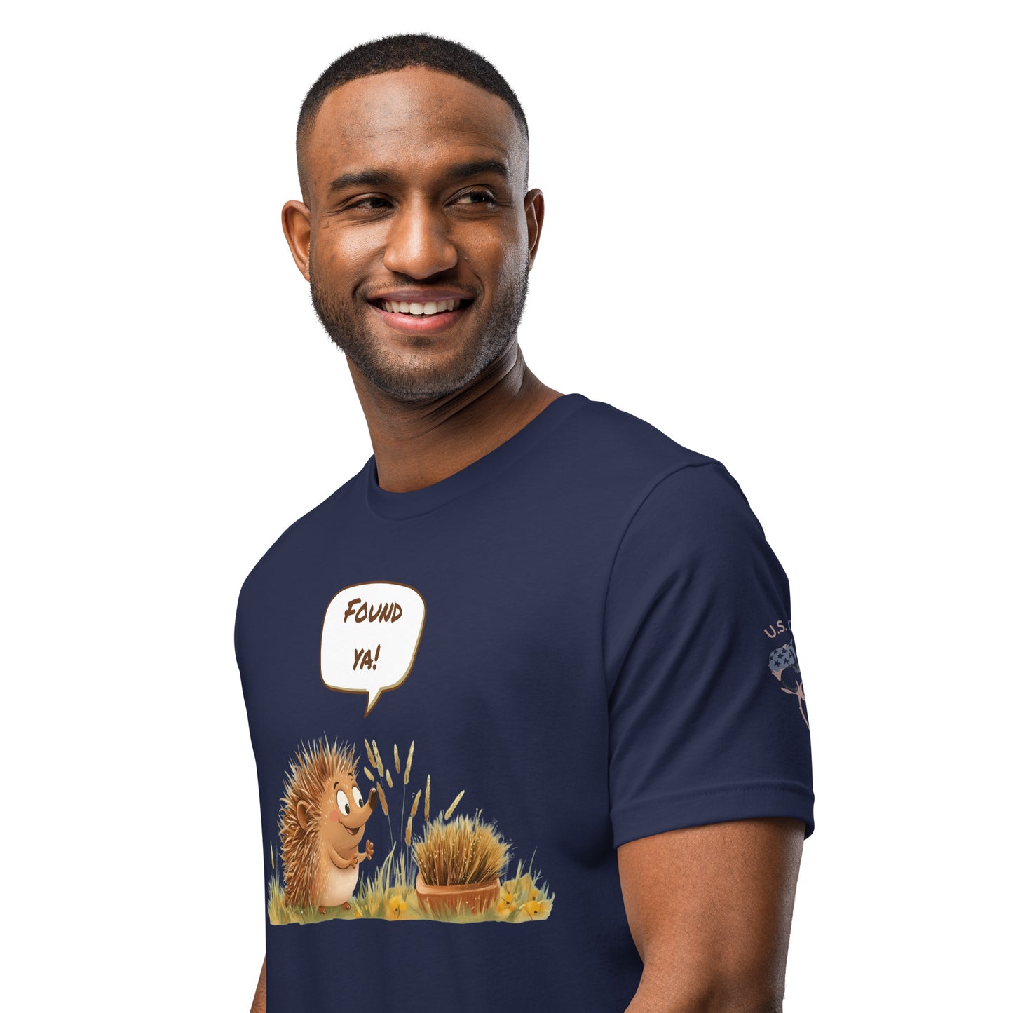 Product mockup. Smiling man wearing a navy blue T-shirt featuring a cartoon hedgehog and a bush, with the speech bubble "Found ya!"