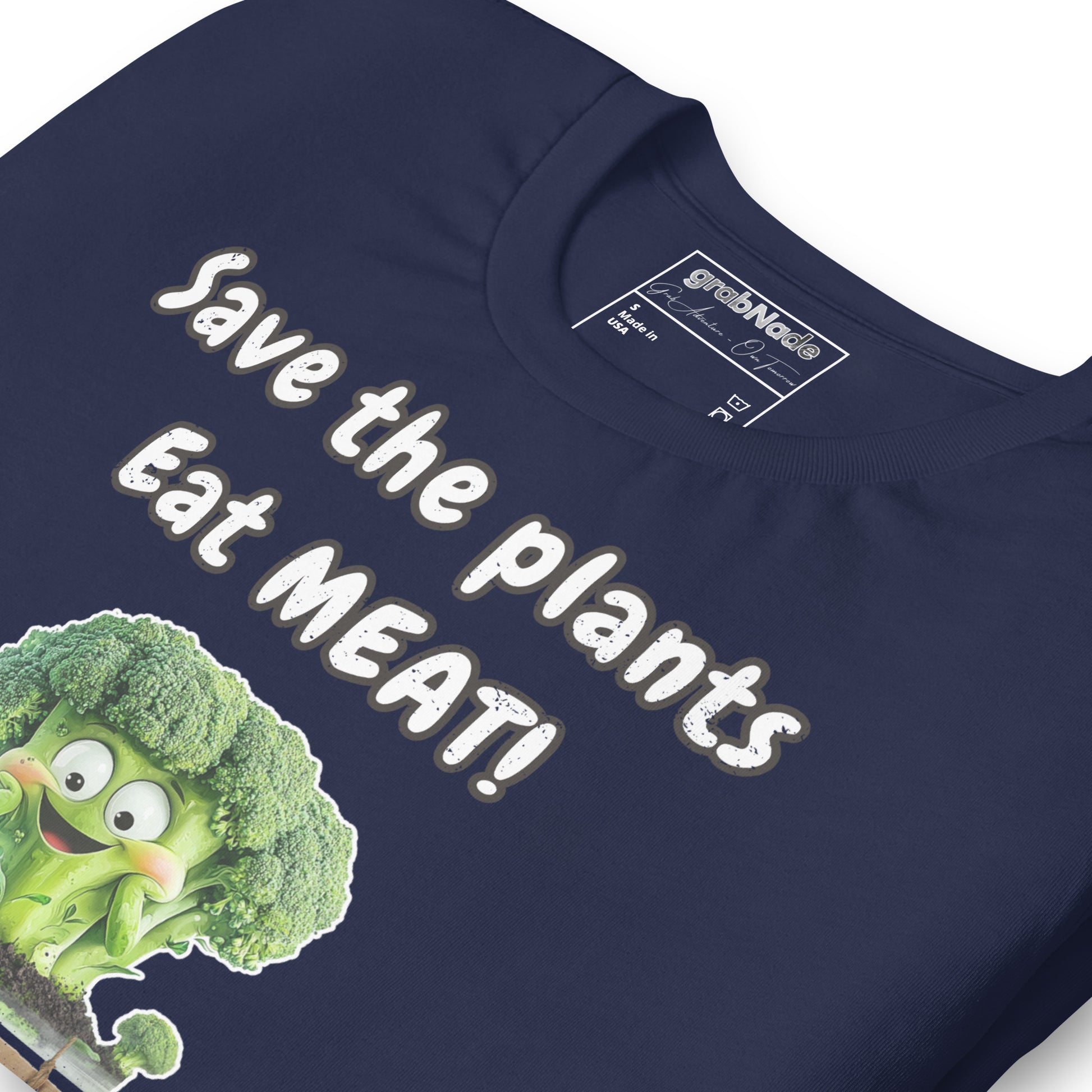 Product mockup. Close-up of navy blue T-shirt fabric displaying the slogan "Save the plants Eat MEAT!" with a smiling cartoon broccoli.