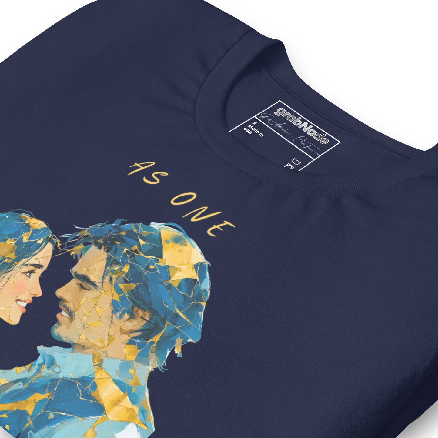 Product mockup. Close-up of navy blue T-shirt with two stylized faces in blue and gold and the text "AS ONE" above.