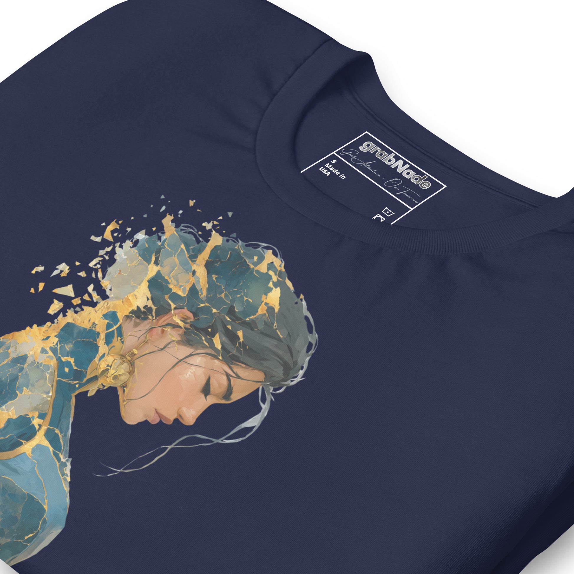 Product mockup. Close-up of navy blue T-shirt with illustrated woman in blue and gold, head bowed and abstract fragments above.
