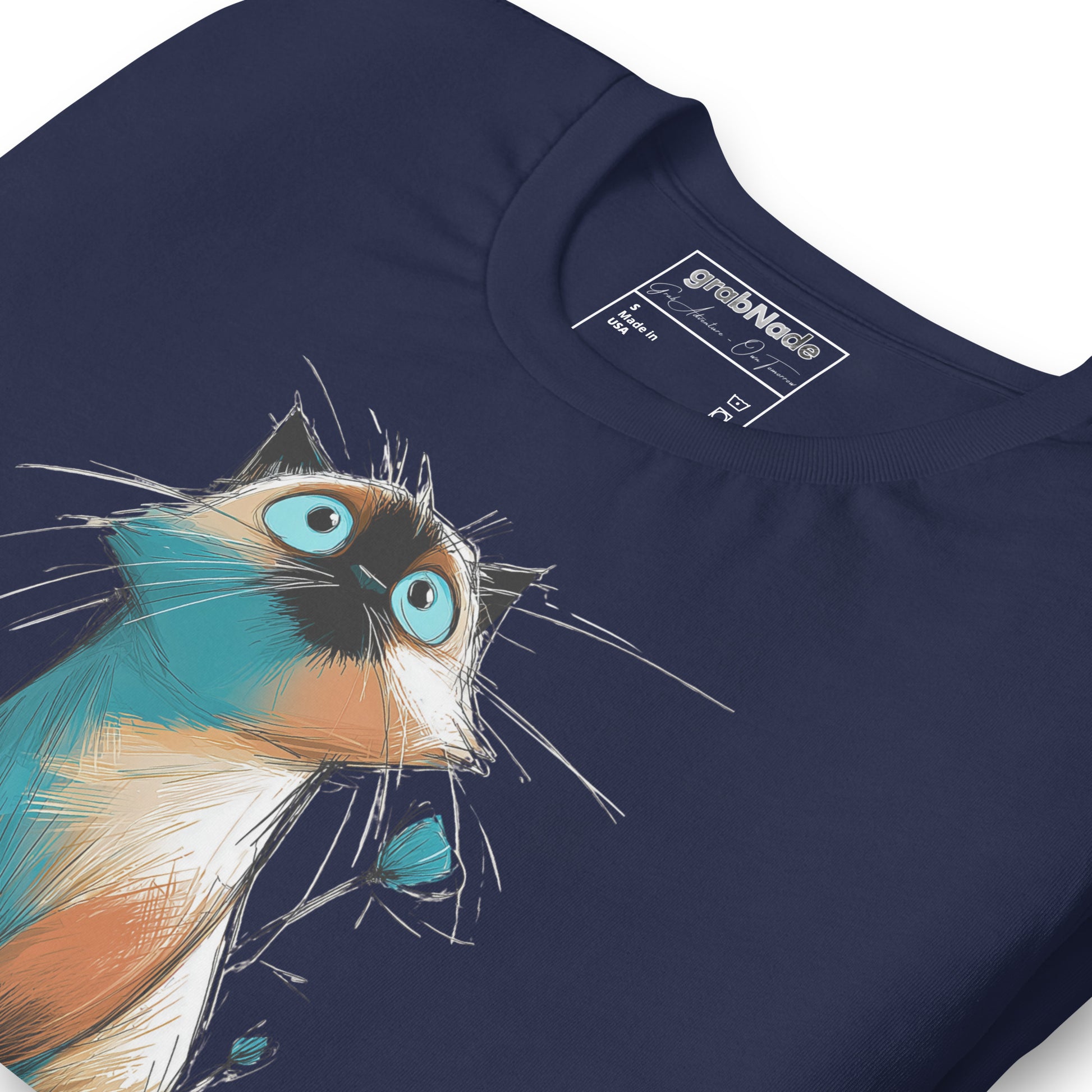Product mockup. Close-up of navy blue T-shirt with a blue-eyed cartoon cat in blue and tan, drawn in a lively sketch.