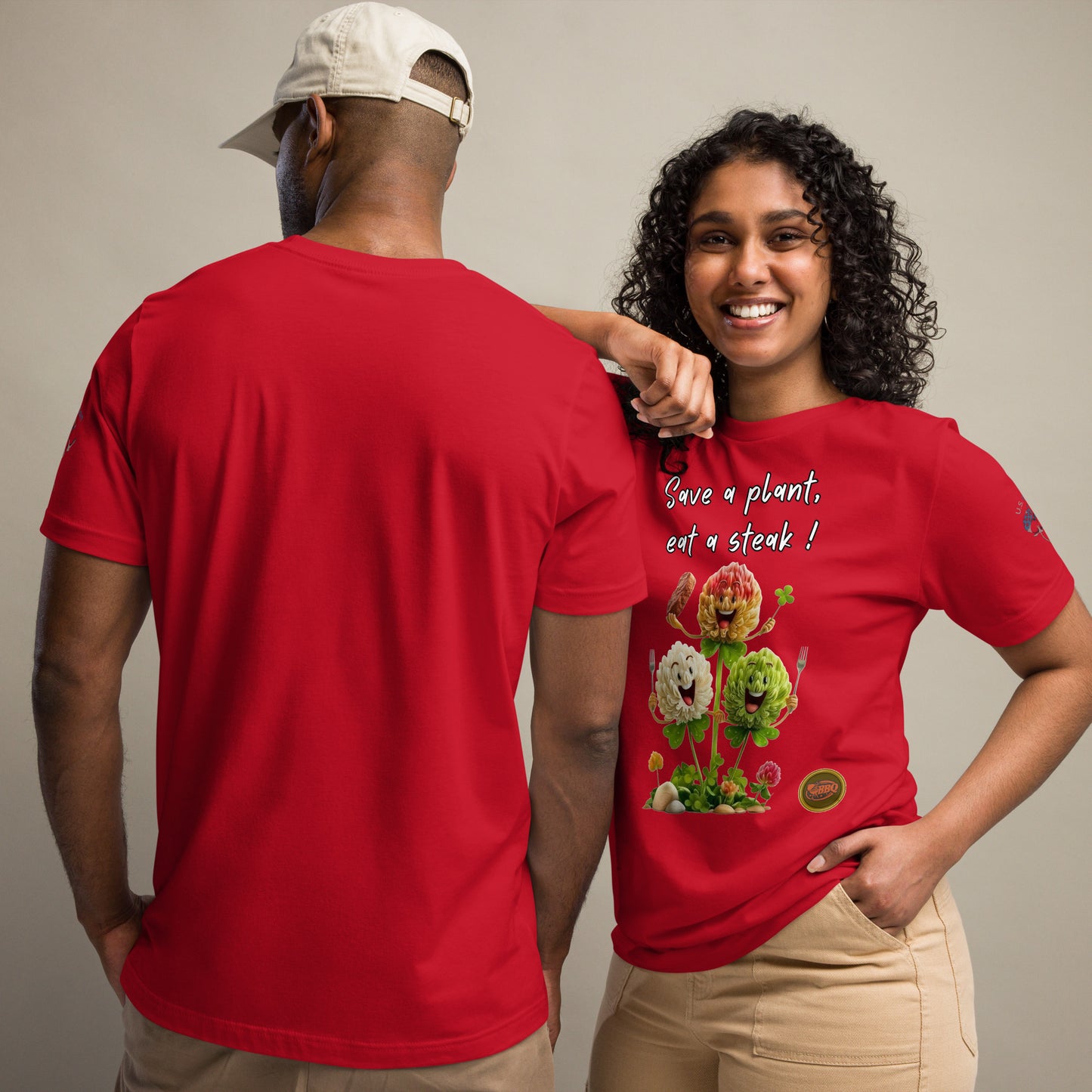 Product mockup. Man and woman standing; woman in front in red T-shirt with text "Save a plant, eat a steak!" and smiling humanoid clovers graphics; man has blank back view.