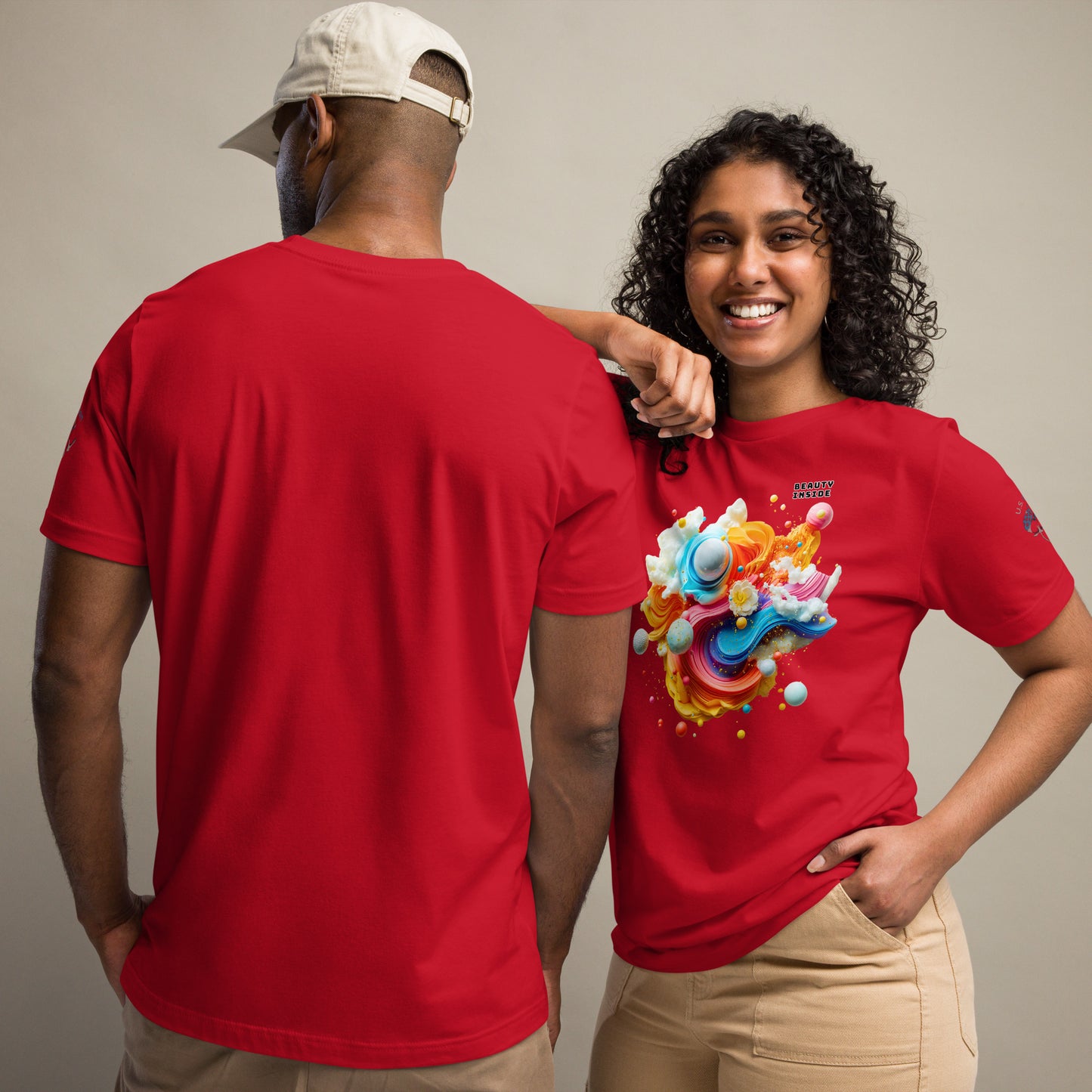 Product mockup. Man and woman; woman wears red T-shirt with vibrant abstract swirling 3D shapes, text "BEAUTY INSIDE", man in plain red shirt back view.