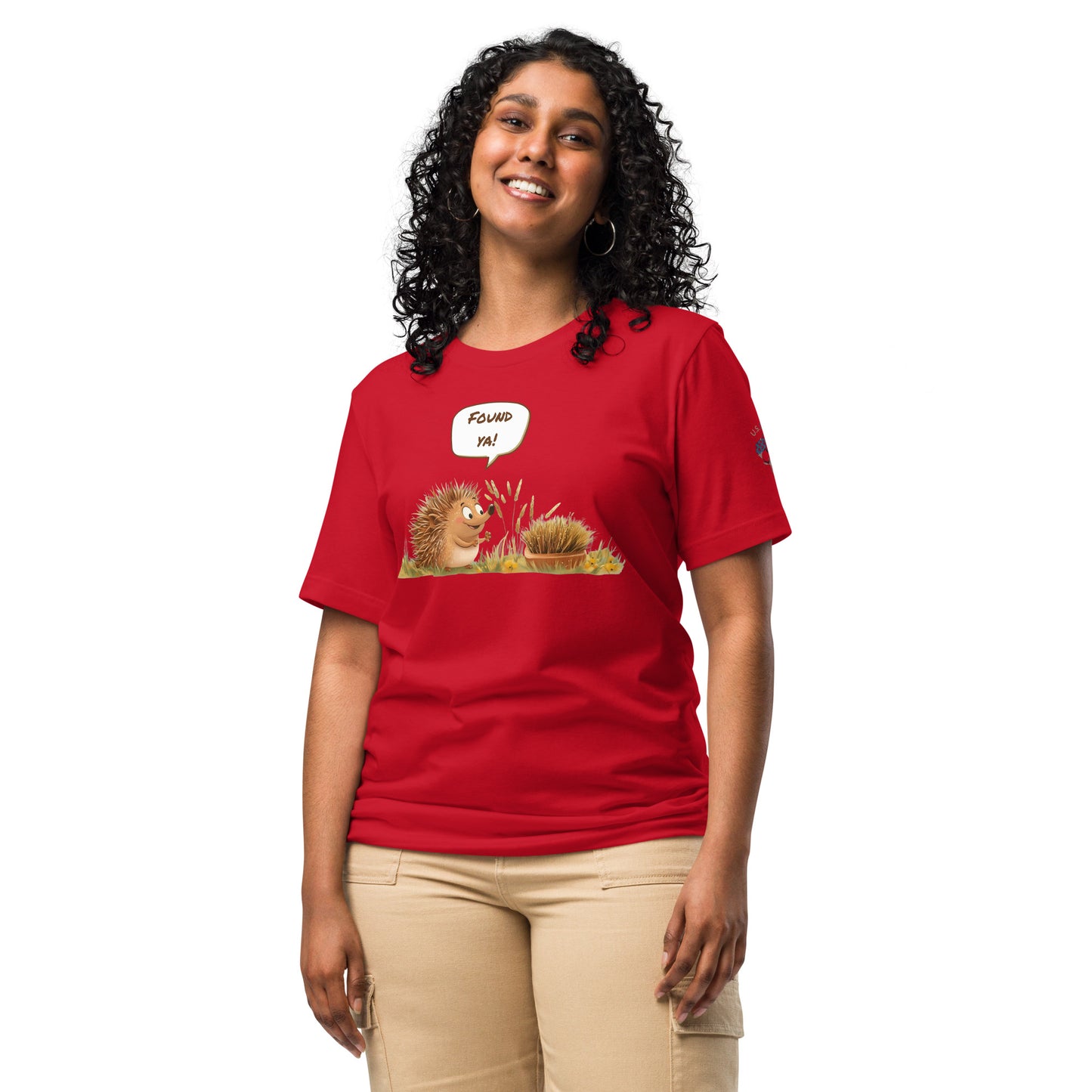 Product mockup. Woman in red T-shirt with cute cartoon hedgehog in grass, speech bubble says “Found ya!”.
