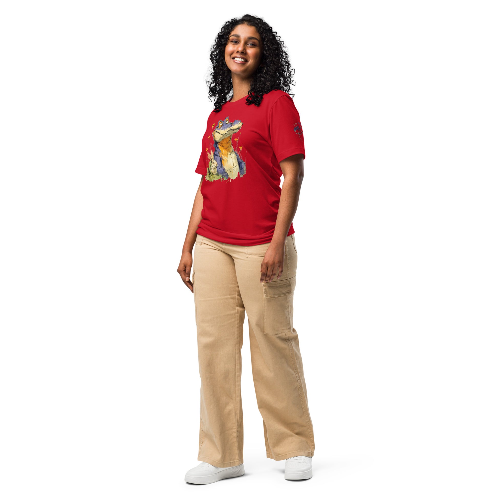 Product mockup. A woman dressed in loose beige pants and a red T-shirt with a large cartoon alligator graphic, posing for a full-body photo.