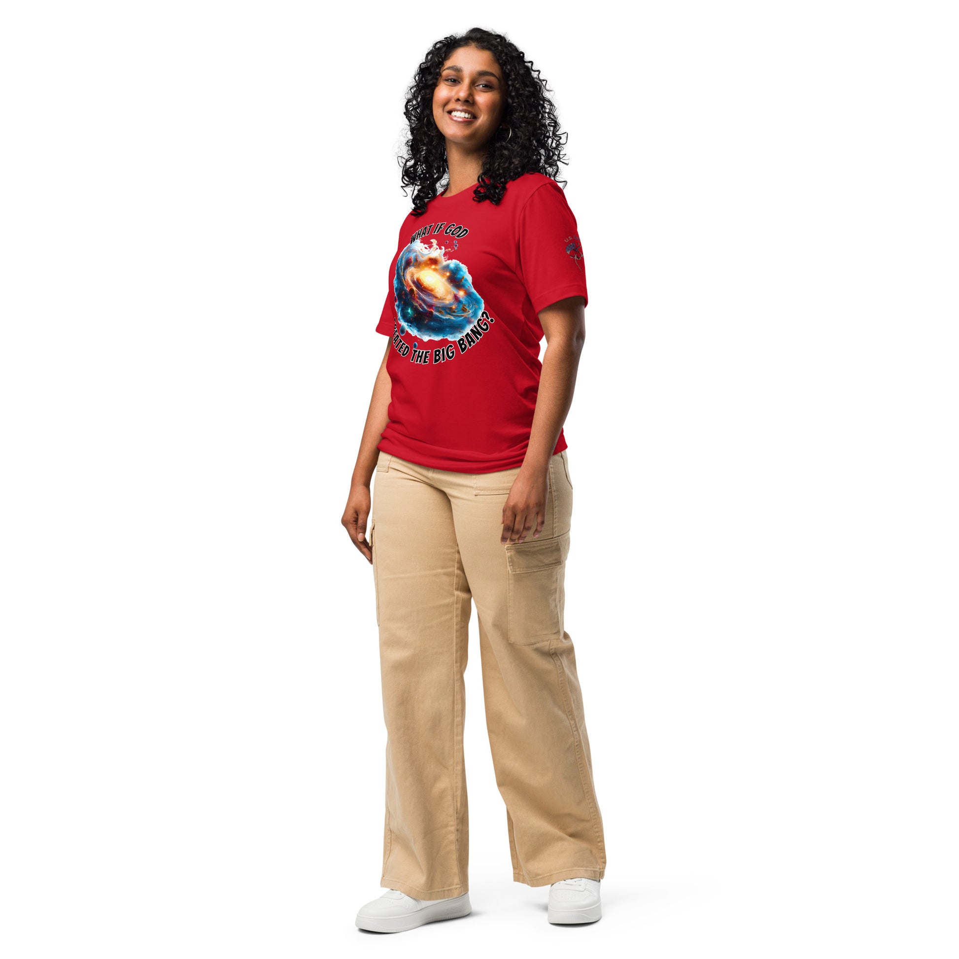 Product mockup. A woman dressed in beige pants and a red T-shirt printed with a dramatic cosmic galaxy design and the words “WHAT IF GOD CREATED THE BIG BANG?”, shown in a full-body pose.