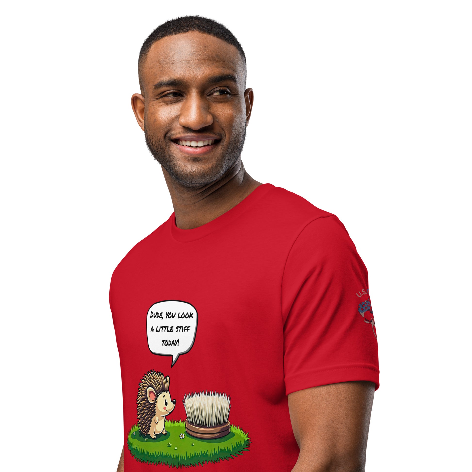 Product mockup. A man wearing a red T-shirt with a cartoon hedgehog saying “Dude, you look a little stiff today!” to a brush resembling a hedgehog, shown from the waist up.