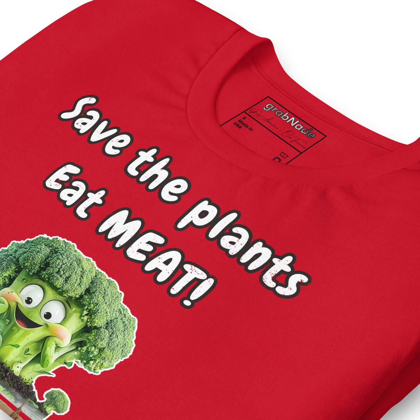 Product mockup. Close-up of a red T-shirt with a large, happy cartoon broccoli and the phrase “Save the plants Eat MEAT!”, shown near the collar.