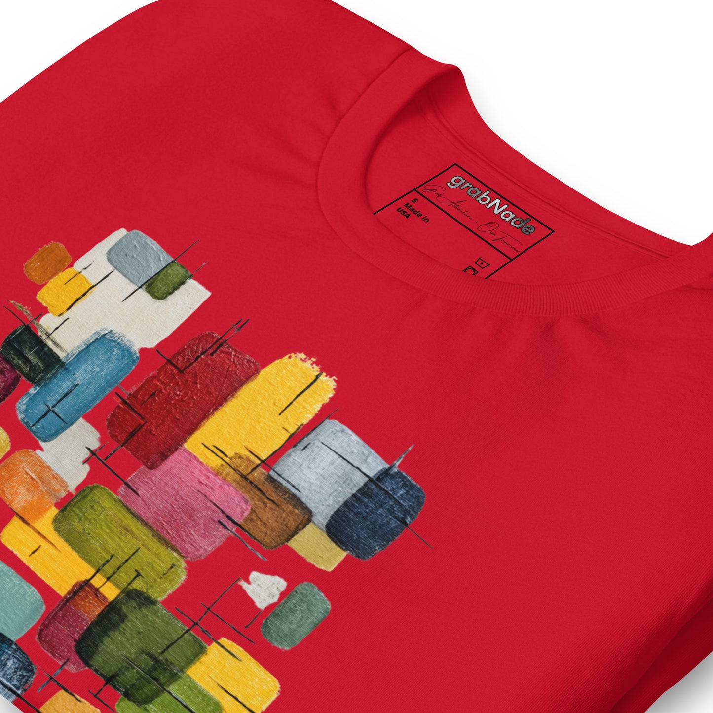 Product mockup. Zoomed-in detail of a red T-shirt displaying a bold, colorful abstract geometric painting made up of rectangles in blue, yellow, green, red, and pink.