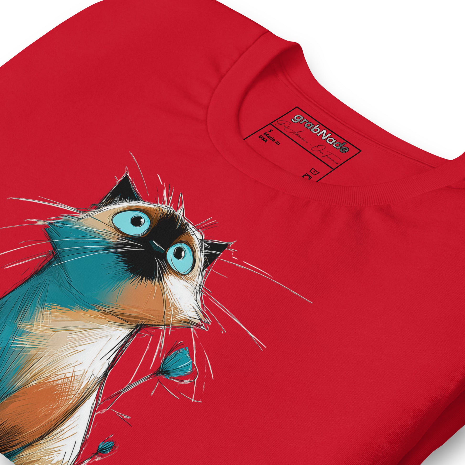Product mockup. Close-up of a red T-shirt featuring a cartoon-style wide-eyed cat in shades of blue, tan, and black, looking upward.