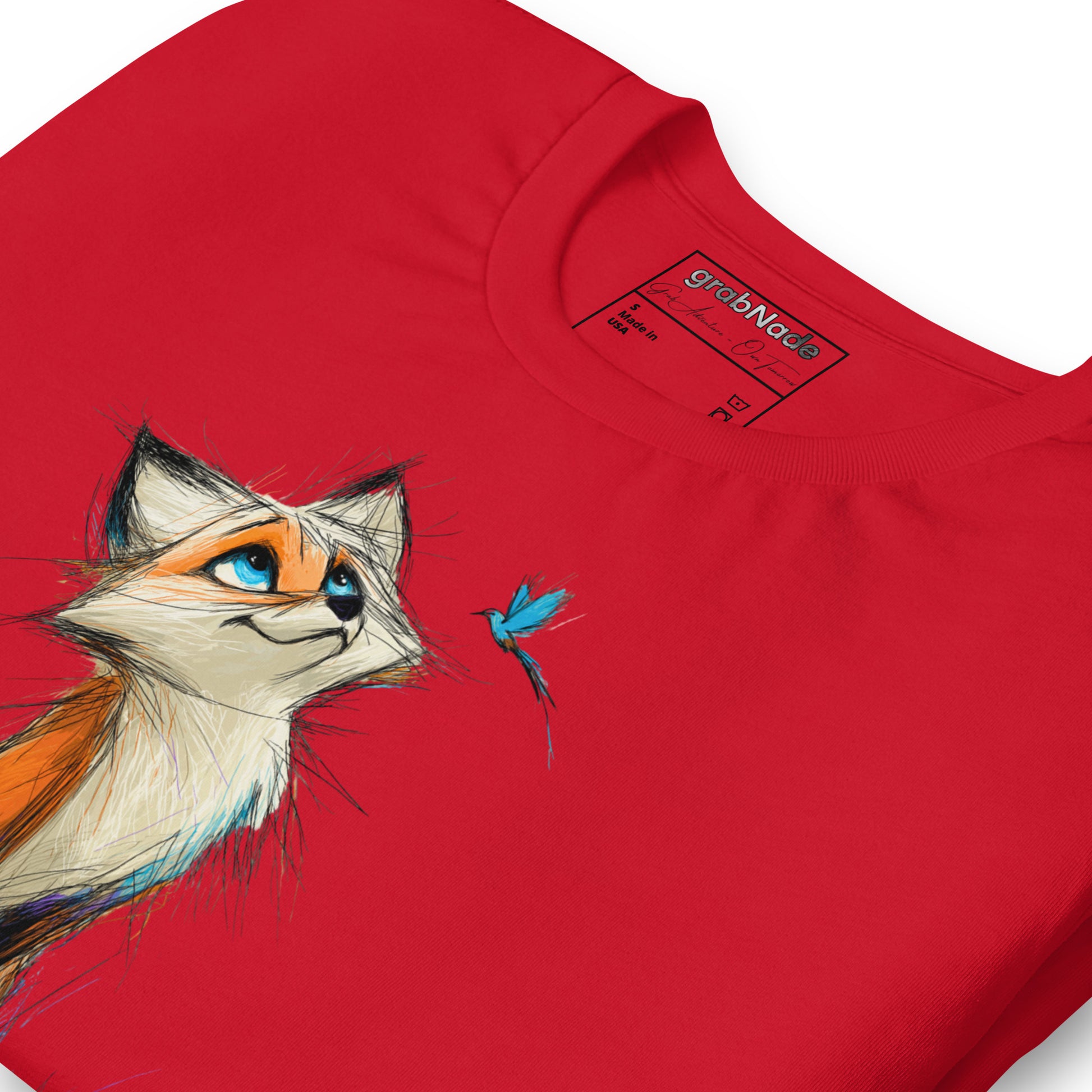 Product mockup. Close-up of a red T-shirt showing a whimsical orange, white, and brown cartoon fox facing a small blue bird.