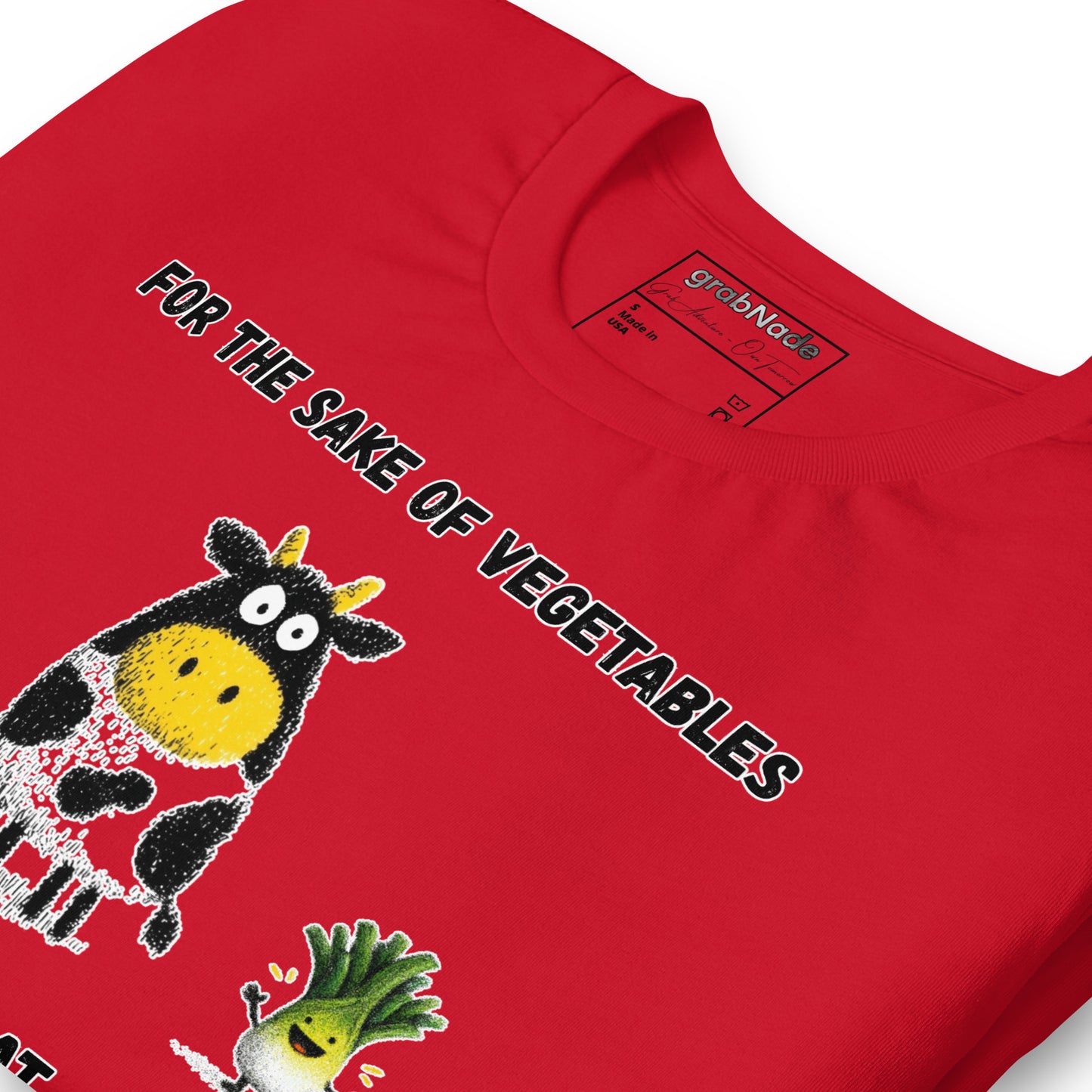 Product mockup. Close-up of a red T-shirt decorated with a big cartoon cow and vegetable characters, with the slogan “FOR THE SAKE OF VEGETABLES I EAT MEAT.”