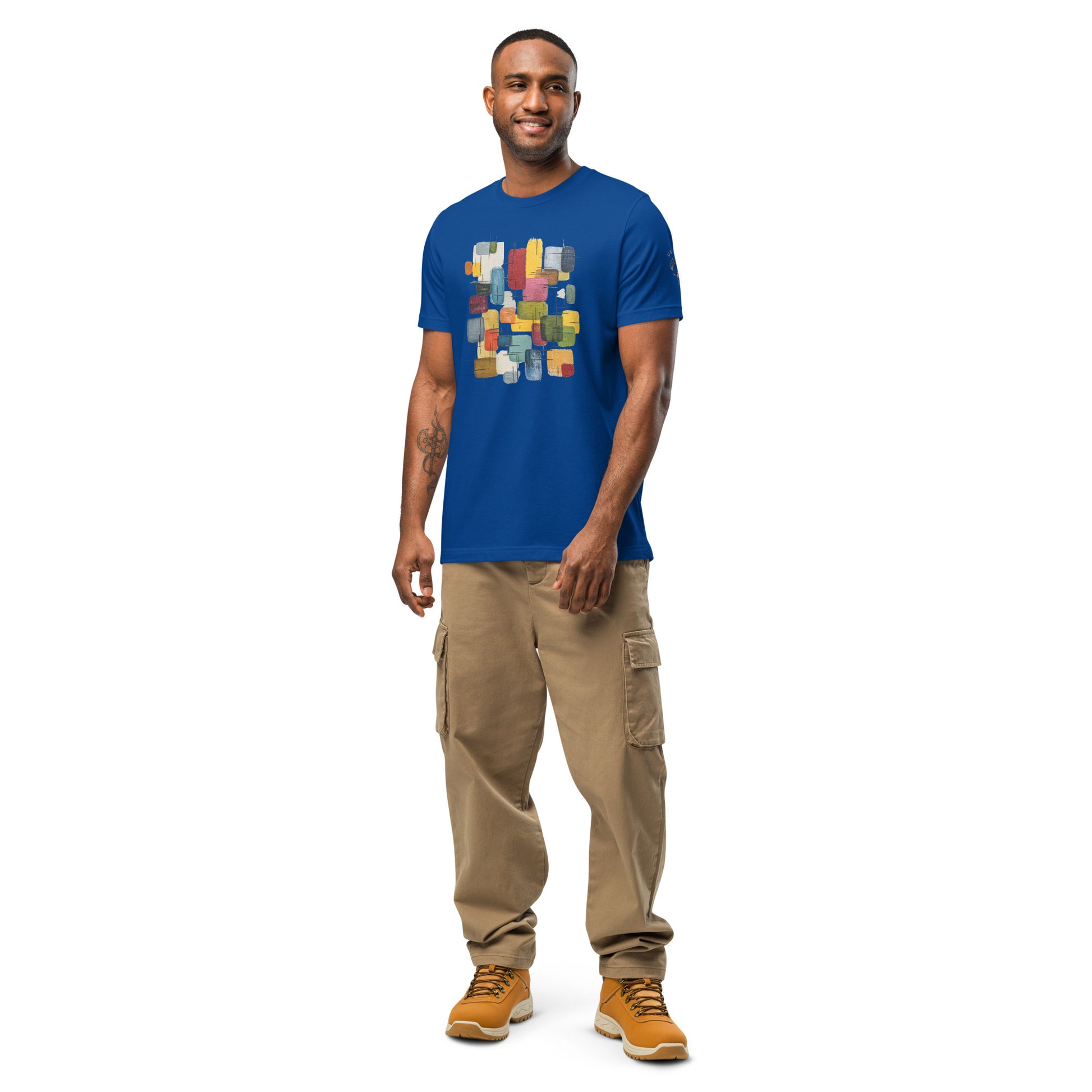 Product mockup. A man standing in tan cargo pants and boots, modeling a royal blue T-shirt with a centered abstract rectangles print in various colors.