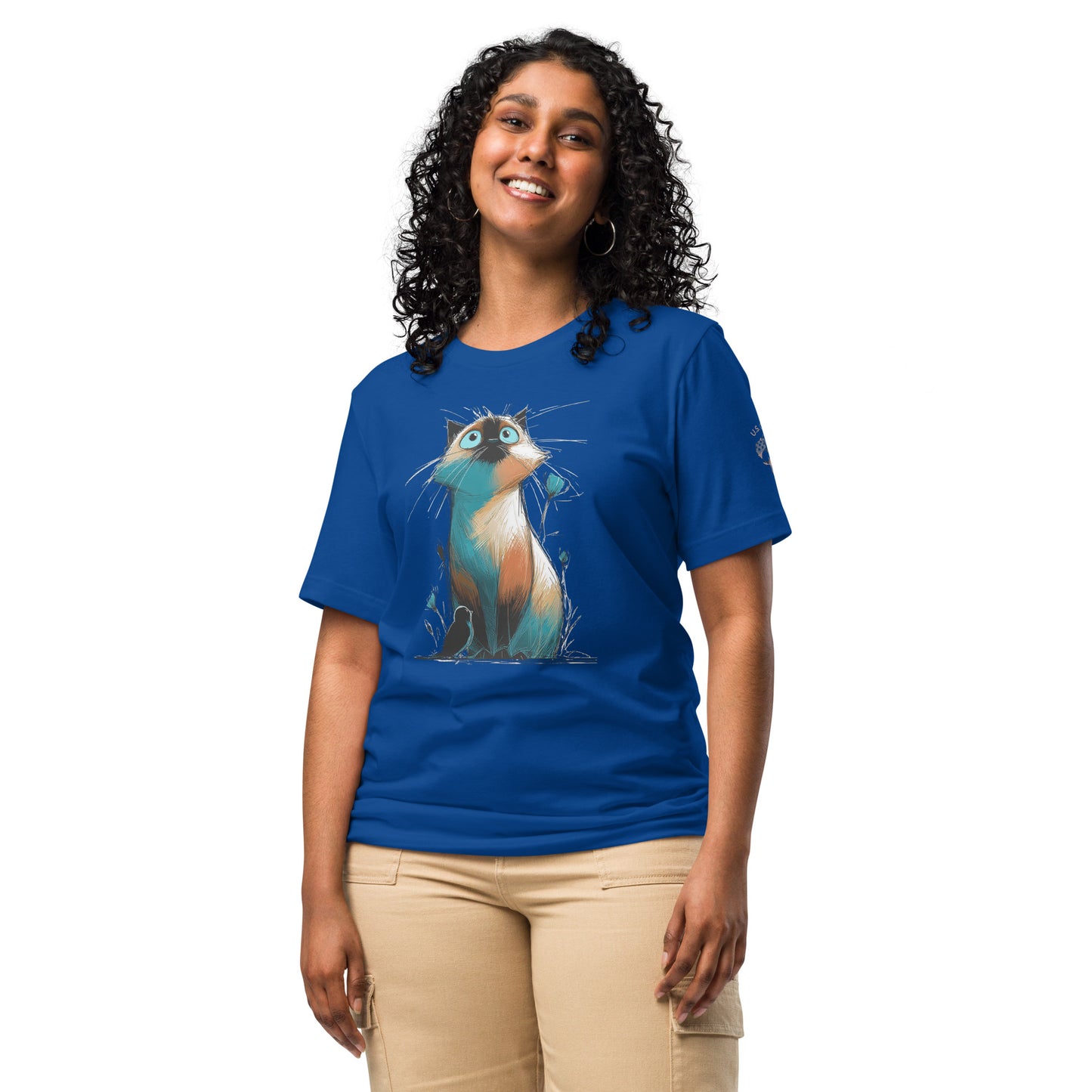 Product mockup. Woman in blue T-shirt with cartoon-style, wide-eyed cat illustration sitting among abstract grass and flowers.
